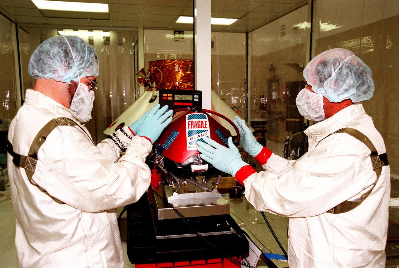 KENNEDY SPACE CENTER, FLA. -- In the Spacecraft Assembly and Encapsulation Facility -2 (SAEF-2), two JPL workers measure a Mars microprobe. Two microprobes will hitchhike on the Mars Polar Lander, scheduled to be launched Jan. 3, 1999, aboard a Delta II rocket. The solar-powered spacecraft is designed to touch down on the Martian surface near the northern-most boundary of the south pole in order to study the water cycle there. The lander also will help scientists learn more about climate change and current resources on Mars, studying such things as frost, dust, water vapor and condensates in the Martian atmosphere. The Mars microprobes, called Deep Space 2, are part of NASA's New Millennium Program. They will complement the climate-related scientific focus of the lander by demonstrating an advanced, rugged microlaser system for detecting subsurface water. Such data on polar subsurface water, in the form of ice, should help put limits on scientific projections for the global abundance of water on Mars
