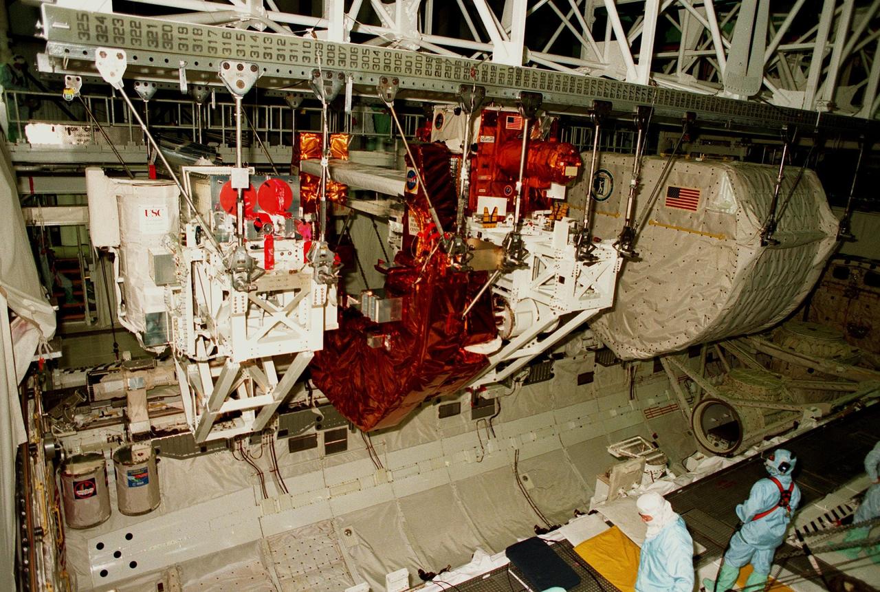 KENNEDY SPACE CENTER, FLA. -- Workers in the Orbiter Processing Facility watch as the STS-95 payloads are lifted from the cargo bay of the orbiter Discovery by the overhead crane. The experiments will be returned to their respective hosts. At the right is the SPACEHAB single module with experiments on space flight and the aging process. The other payloads include the Spartan solar-observing deployable spacecraft, the Hubble Space Telescope Orbital Systems Test Platform, and the International Extreme Ultraviolet Hitchhiker