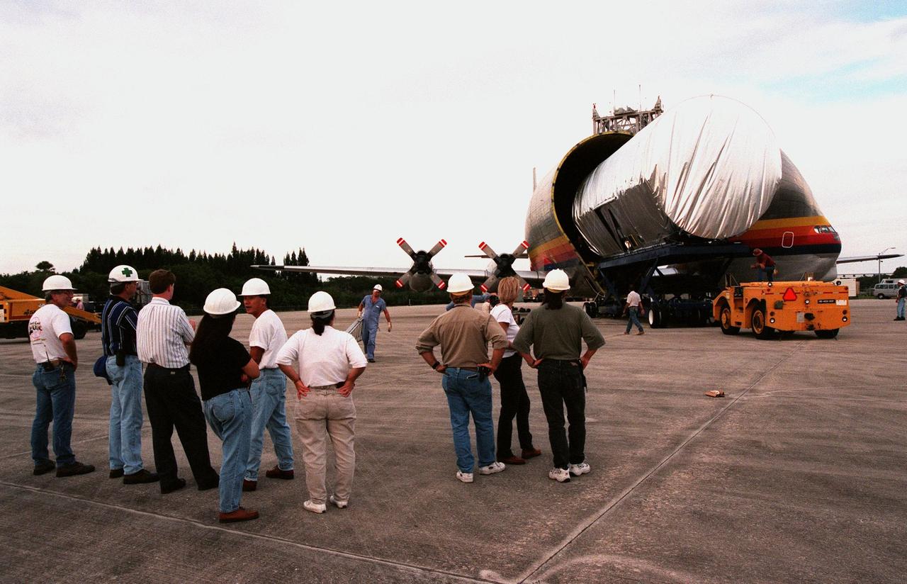 KENNEDY SPACE CENTER, FLA. -- Workers at the Shuttle Landing Facility watch as the canister carrying the U.S. laboratory module, intended for the International Space Station, is moved out of NASA's "Super Guppy" aircraft that brought it from Marshall Space Flight Center, Huntsville. The lab is being transferred to the Space Station Processing Facility for pre-launch preparations. Scheduled for launch aboard the Shuttle Endeavour on mission STS-98, the laboratory comprises three cylindrical sections with two end cones. Each end-cone contains a hatch opening for entering and exiting the lab. The lab will provide a shirtsleeve environment for research in the areas of life science, microgravity science, Earth science and space science. Designated Flight 5A, this mission is targeted for launch in early 2000