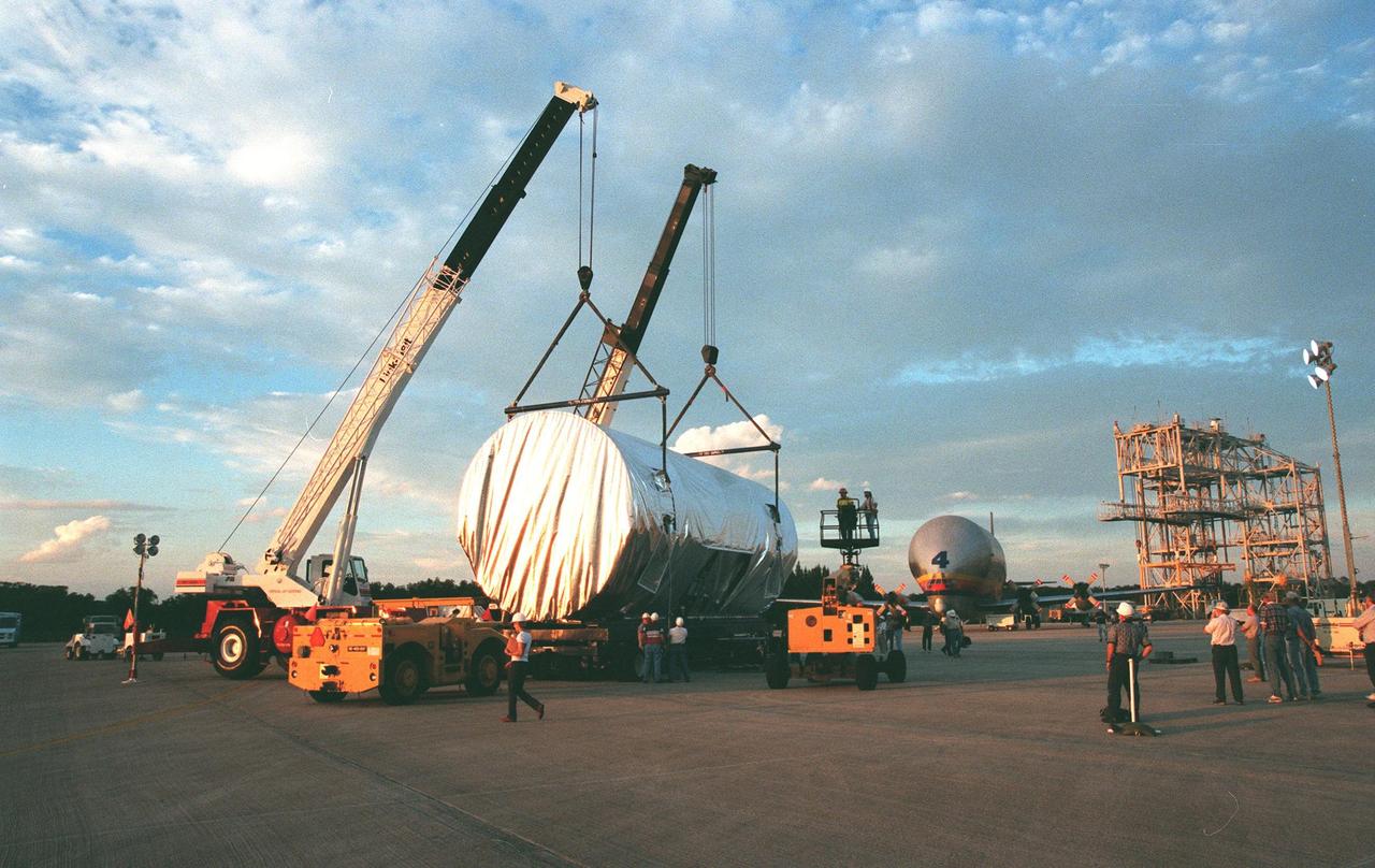 KENNEDY SPACE CENTER, FLA. -- A second crane is attached to the canister containing the U.S. laboratory module in order to transfer it to a truck. Intended for the International Space Station, the lab is being moved to the Space Station Processing Facility for pre-launch preparations. Scheduled for launch aboard the Shuttle Endeavour on mission STS-98, the laboratory comprises three cylindrical sections with two end cones. Each end-cone contains a hatch opening for entering and exiting the lab. The lab will provide a shirtsleeve environment for research in the areas of life science, microgravity science, Earth science and space science. Designated Flight 5A, this mission is targeted for launch in early 2000