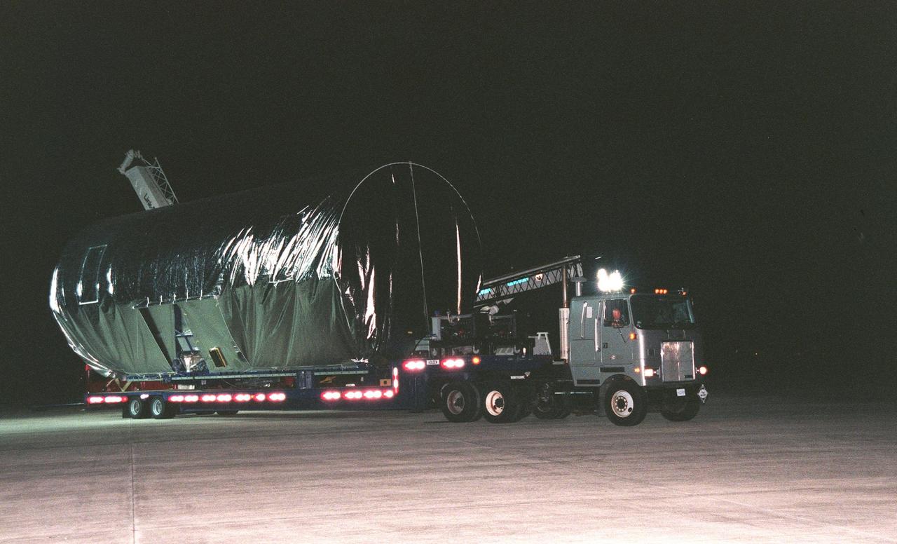 KENNEDY SPACE CENTER, FLA. -- After nightfall, a truck carrying the container that holds the U.S. laboratory module begins the trip from the Shuttle Landing Facility to the Space Station Processing Facility. Intended for the International Space Station, the lab is scheduled to undergo pre-launch preparations before its launch aboard the Shuttle Endeavour on mission STS-98. The laboratory comprises three cylindrical sections with two end cones. Each end-cone contains a hatch opening for entering and exiting the lab. The lab will provide a shirtsleeve environment for research in the areas of life science, microgravity science, Earth science and space science. Designated Flight 5A, this mission is targeted for launch in early 2000