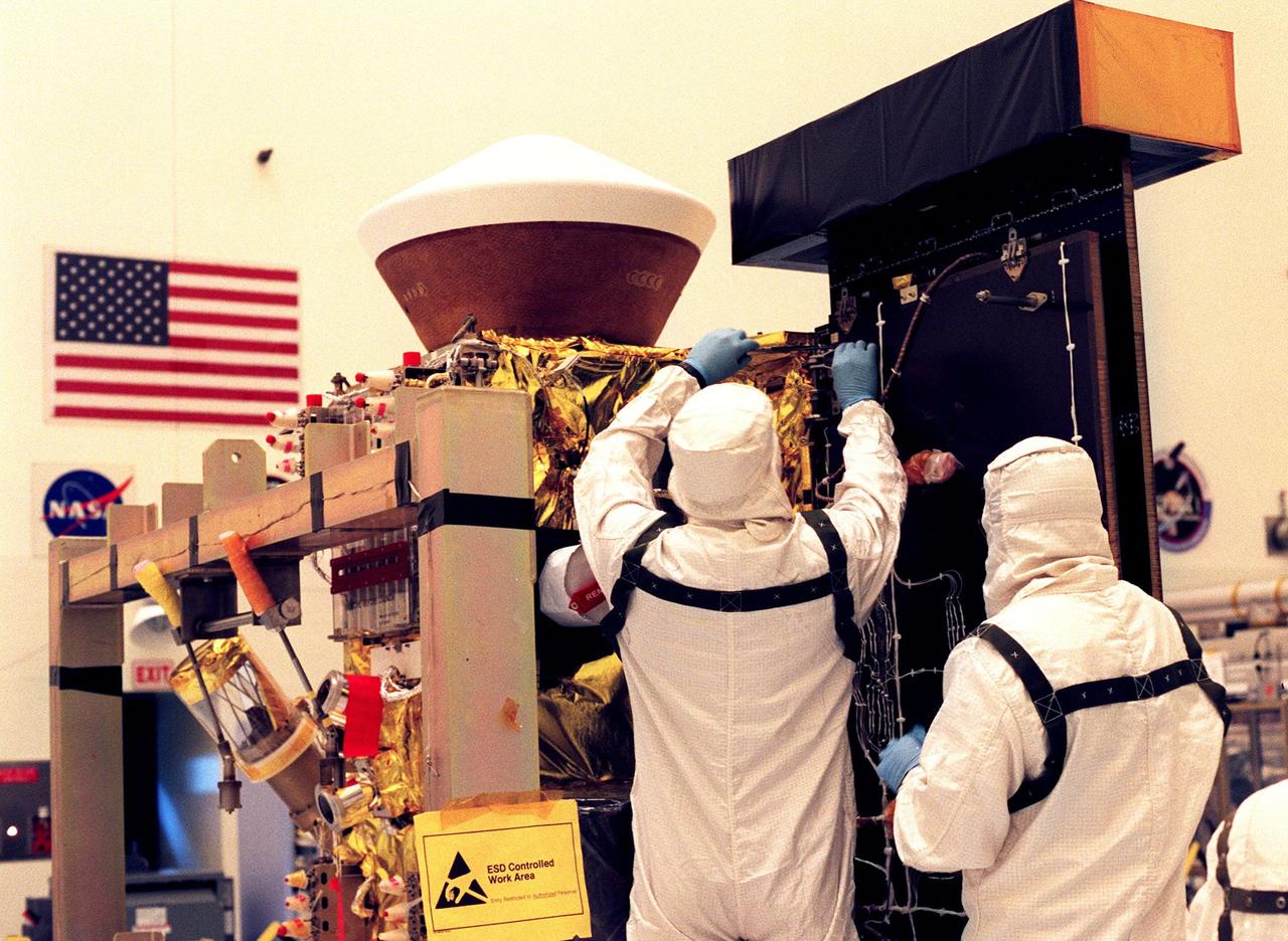 In the Payload Hazardous Servicing Facility, workers remove one of the Stardust solar panels for testing. The spacecraft Stardust will be launched aboard a Boeing Delta 7426 rocket from Complex 17, Cape Canaveral Air Station, targeted for Feb. 6, 1999. Stardust will use a unique medium called aerogel to capture comet particles flying off the nucleus of comet Wild 2 in January 2004, plus collect interstellar dust for later analysis. The collected samples will return to Earth in a re-entry capsule (seen on top, next to the solar panel) to be jettisoned from Stardust as it swings by Earth in January 2006