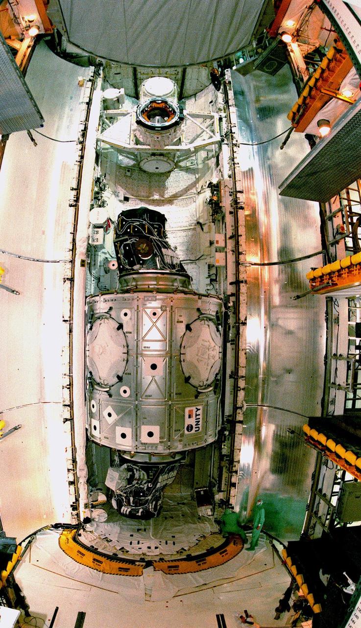 This fish-eye view of the Unity connecting module reveals its immense size relative to the workers (below right). Unity rests inside the open payload bay of the orbiter Endeavour on Launch Pad 39A. At the top of bay is the docking mechanism first used with launches to Mir, the Russian space station. Unity is the first U.S. element of the International Space Station (ISS) and is scheduled for launch Dec. 3, 1998, on Mission STS-88. The Unity is a connecting passageway to the living and working areas of ISS. While on orbit, the flight crew will deploy Unity from the payload bay and attach it to the Russian-built Zarya control module which will be in orbit at that time. The mission is expected to last nearly 12 days, landing back at the Kennedy Space Center on Dec. 14