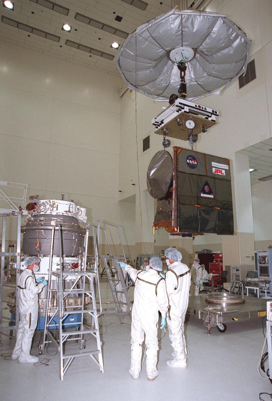 KENNEDY SPACE CENTER, FLA. -- In the Spacecraft Assembly and Encapsulation Facility -2 (SAEF-2), the Mars Climate Orbiter (right) is lifted to move it for mating to the third stage of the Boeing Delta II launch vehicle waiting at left. The third stage is a solid-propellant Thiokol Star 48B booster, the same final stage used in the 1996 launch of Mars Global Surveyor. Targeted for launch on Dec. 10, 1998, the orbiter is heading for Mars where it will primarily support its companion Mars Polar Lander spacecraft, which is planned for launch on Jan. 3, 1999. The orbiter's instruments will monitor the Martian atmosphere and image the planet's surface on a daily basis for 687 Earth days. It will observe the appearance and movement of atmospheric dust and water vapor, as well as characterize seasonal changes on the surface. The detailed images of the surface features will provide important clues to the planet's early climate history and give scientists more information about possible liquid water reserves beneath the surface. <BR>; <BR>; <BR> <BR> <BR> <CENTER