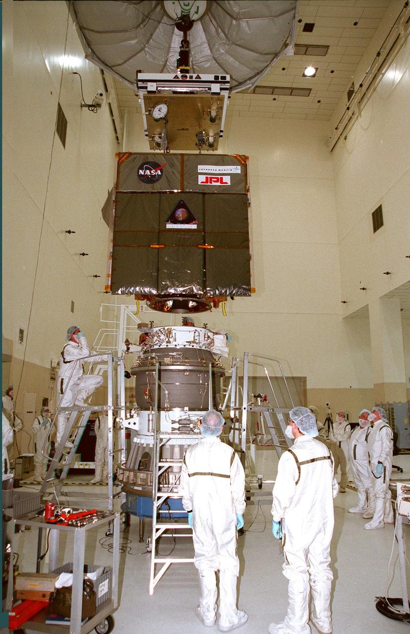 KENNEDY SPACE CENTER, FLA. -- In the Spacecraft Assembly and Encapsulation Facility -2 (SAEF-2), the Mars Climate Orbiter (top) is lowered toward the third stage of the Boeing Delta II launch vehicle below it, to which it will be attached. The third stage is a solid-propellant Thiokol Star 48B booster, the same final stage used in the 1996 launch of Mars Global Surveyor. Targeted for launch on Dec. 10, 1998, the orbiter is heading for Mars where it will primarily support its companion Mars Polar Lander spacecraft, which is planned for launch on Jan. 3, 1999. The orbiter's instruments will monitor the Martian atmosphere and image the planet's surface on a daily basis for 687 Earth days. It will observe the appearance and movement of atmospheric dust and water vapor, as well as characterize seasonal changes on the surface. The detailed images of the surface features will provide important clues to the planet's early climate history and give scientists more information about possible liquid water reserves beneath the surface