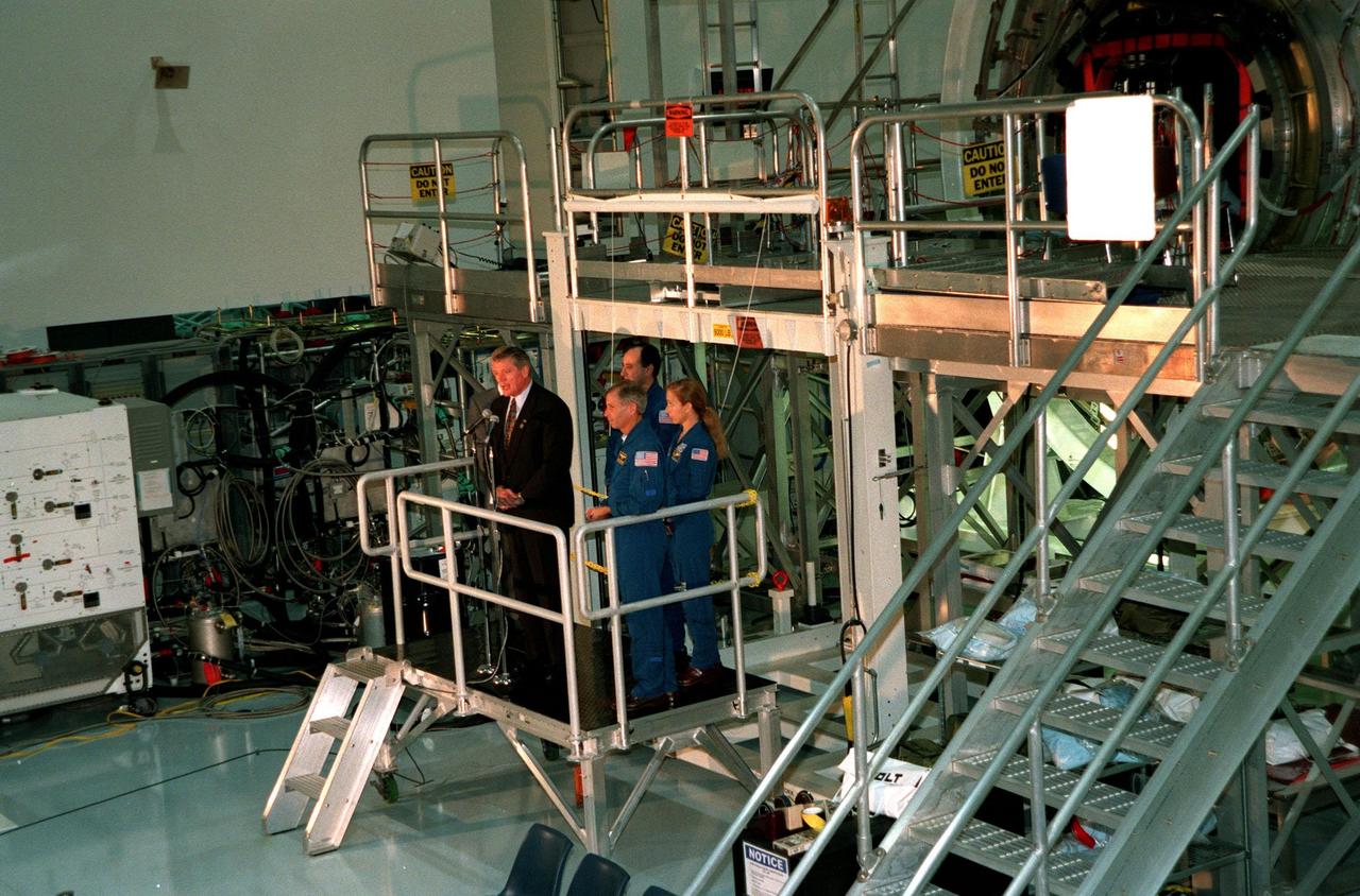 KENNEDY SPACE CENTER, FLA. -- In the Space Station Processing Facility, Program Manager of the International Space Station (ISS) Randy Brinkley addresses the media before unveiling the name of "Destiny" given the U.S. Lab module, the centerpiece of scientific research on the ISS. With Brinkley on the stand are Center Director Roy Bridges (behind him), and (left to right) STS-98 Commander Ken Cockrell, Pilot Mark Polansky, and Mission Specialist Marsha Ivins. The lab, which is behind them on a workstand, is scheduled to be launched on Space Shuttle Endeavour in early 2000. It will become the centerpiece of scientific research on the International Space Station. Polansky, Cockrell and Ivins are part of the five-member crew expected to be aboard. The Shuttle will spend six days docked to the station while the laboratory is attached and three space walks are conducted to complete its assembly. The laboratory will be launched with five equipment racks aboard, which will provide essential functions for station systems, including high data-rate communications, and maintain the station's orientation using control gyroscopes launched earlier. Additional equipment and research racks will be installed in the laboratory on subsequent Shuttle flights