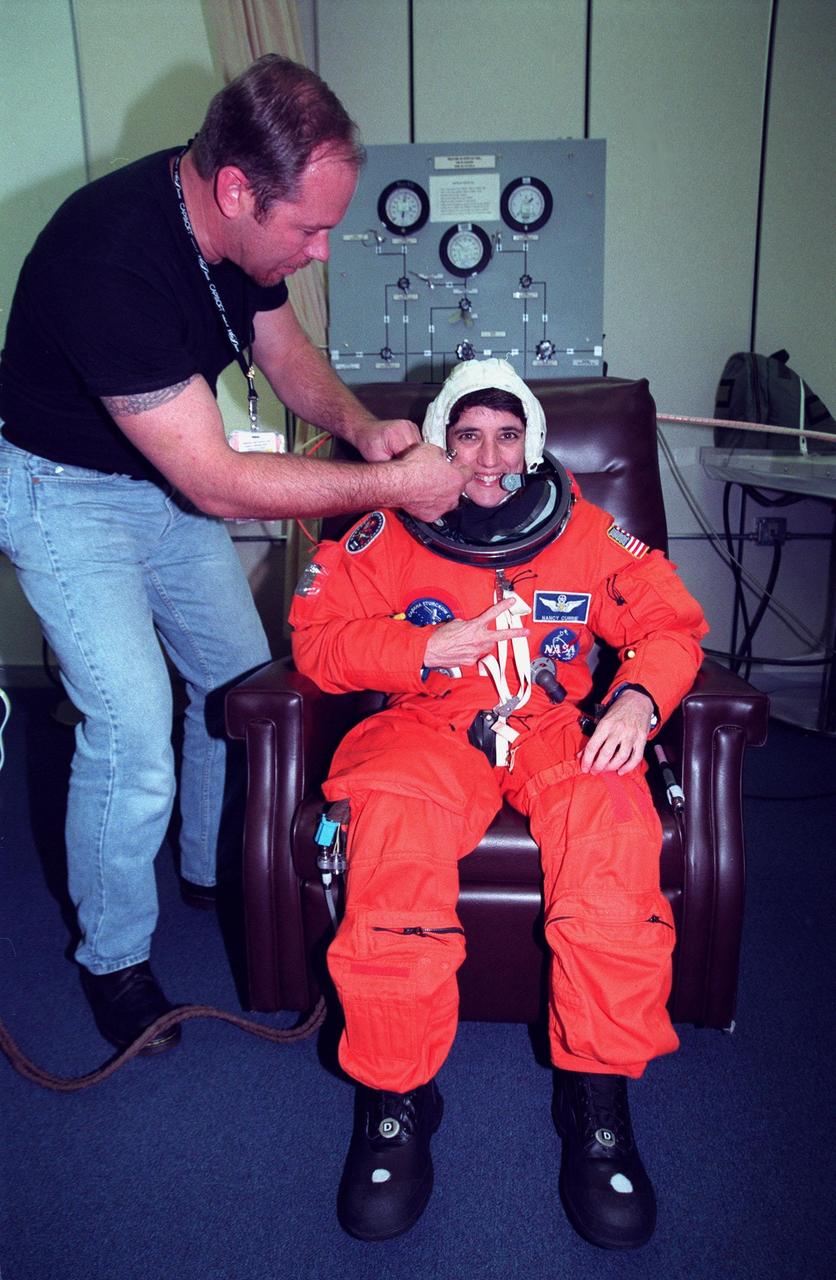 In the Operations and Checkout Building, STS-88 Mission Specialist Nancy J. Currie gets help with her flight suit from suit technician Drew Billingsley before launch. Mission STS-88 is expected to launch at 3:56 a.m. EST with the six-member crew aboard Space Shuttle Endeavour on Dec. 3. Endeavour carries the Unity connecting module, which the crew will be mating with the Russian-built Zarya control module already in orbit. In addition to Unity, two small replacement electronics boxes are on board for possible repairs to Zarya batteries. The mission is expected to last 11 days, 19 hours and 49 minutes, landing at 10:17 p.m. EST on Dec. 14