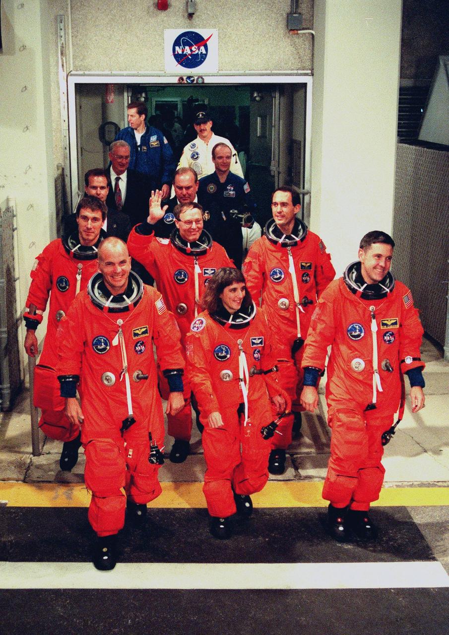 The STS-88 crew leave the Operations and Checkout Building for their trip to Launch Pad 39A. In the front row (left to right) are Pilot Frederick W. "Rick" Sturckow, Mission Specialist Nancy J. Currie and Commander Robert D. Cabana. Behind them (left to right) are Mission Specialist Sergei Konstantinovich Krikalev, a Russian cosmonaut, and Mission Specialists Jerry L. Ross and James H. Newman. STS-88 is expected to launch at 3:56 a.m. EST with the six-member crew aboard Space Shuttle Endeavour on Dec. 3. Endeavour carries the Unity connecting module, which the crew will be mating with the Russian-built Zarya control module already in orbit. In addition to Unity, two small replacement electronics boxes are on board for possible repairs to Zarya batteries. The mission is expected to last 11 days, 19 hours and 49 minutes, with landing at 10:17 p.m. EST on Dec. 14