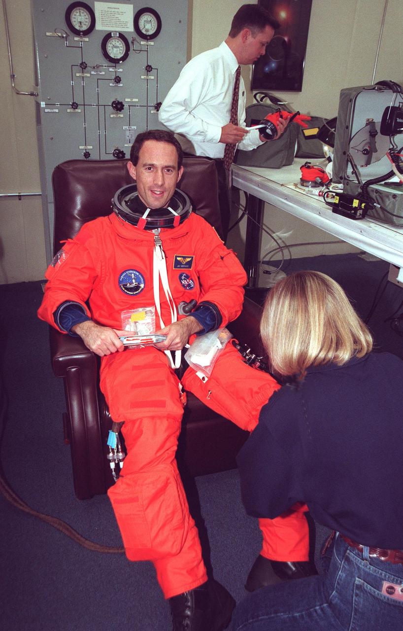 STS-88 Mission Specialist James H. Newman gets assistance from suit technician Terri McKinney while donning his orange launch and entry suit in the Operations and Checkout Building. STS-88 will be Newman’s third spaceflight. He also is scheduled to perform three spacewalks on the mission. He and the five other STS-88 crew members will depart shortly for Launch Pad 39A where the Space Shuttle Endeavour is poised for liftoff on the first U.S. mission dedicated to the assembly of the International Space Station