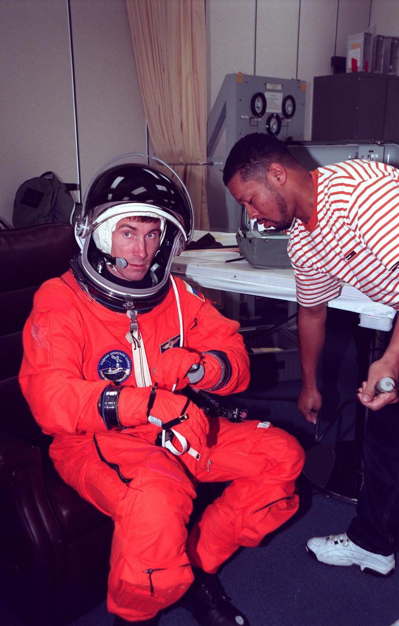 STS-88 Mission Specialist Sergei Konstantinovich Krikalev gets assistance from suit technician George Brittingham while donning his orange launch and entry suit in the Operations and Checkout Building. STS-88 will be Krikalev’s fourth spaceflight, but only his second on the Space Shuttle. He also twice flew on long-duration missions aboard the Russian Space Station Mir. Krikalev and the five other STS-88 crew members will depart shortly for Launch Pad 39A where the Space Shuttle Endeavour is poised for liftoff on the first U.S. mission dedicated to the assembly of the International Space Station
