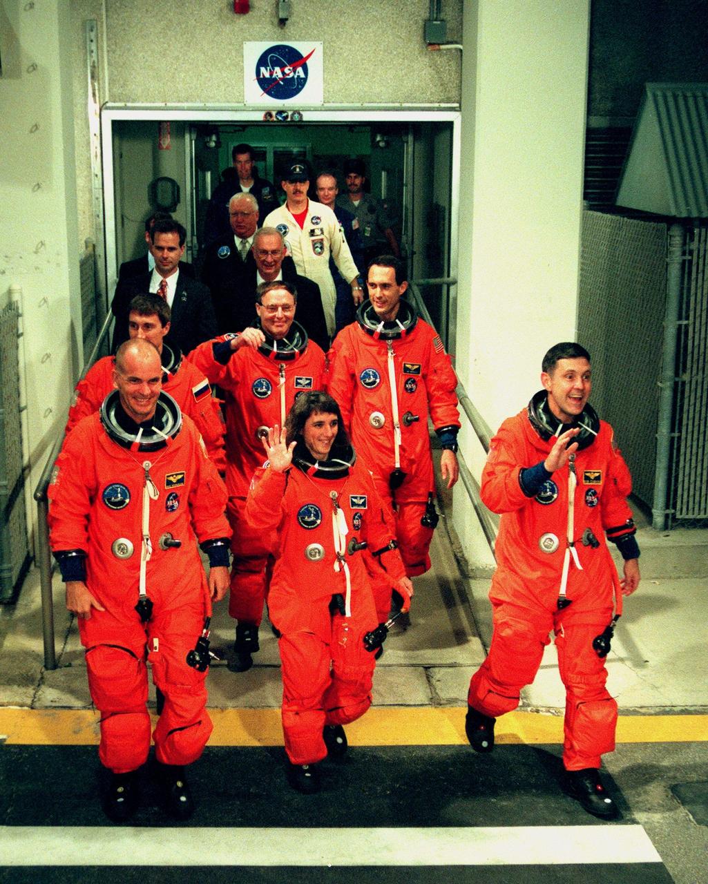 Wearing their orange launch and entry suits, STS-88 crew members leave the Operations and Checkout Building en route to Launch Pad 39A, where the Space Shuttle Endeavour is poised for liftoff of the first U.S. launch dedicated to the assembly of the International Space Station. In front row, from left, are Pilot Frederick W. "Rick" Sturckow, Mission Specialist Nancy J. Currie and Commander Robert D. Cabana. In back row, from left, are Mission Specialists Sergei Konstantinovich Krikalev, a Russian cosmonaut; Jerry L. Ross and James H. Newman. Liftoff is targeted for 3:35 a.m. EST on Dec. 4