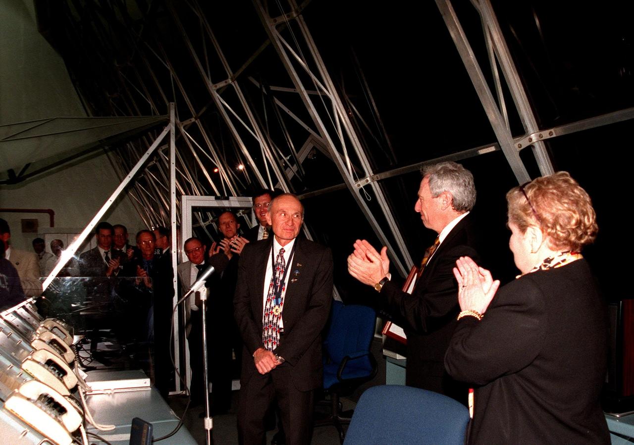 In a firing room in the Launch Control Center, KSC Director of Shuttle Operations Robert B. Sieck (left) is applauded by NASA Administrator Daniel Goldin (center) and U.S. Secretary of State Madeleine Albright for receiving the Distinguished Service Medal (seen around Sieck's neck). Goldin conferred the medal after the successful launch of STS-88, citing Sieck's distinguished service as the Kennedy Space Center launch director and director of Shuttle Processing, outstanding leadership and total dedication to the success of the Space Shuttle Program. The medal is the highest honor NASA gives a government employee