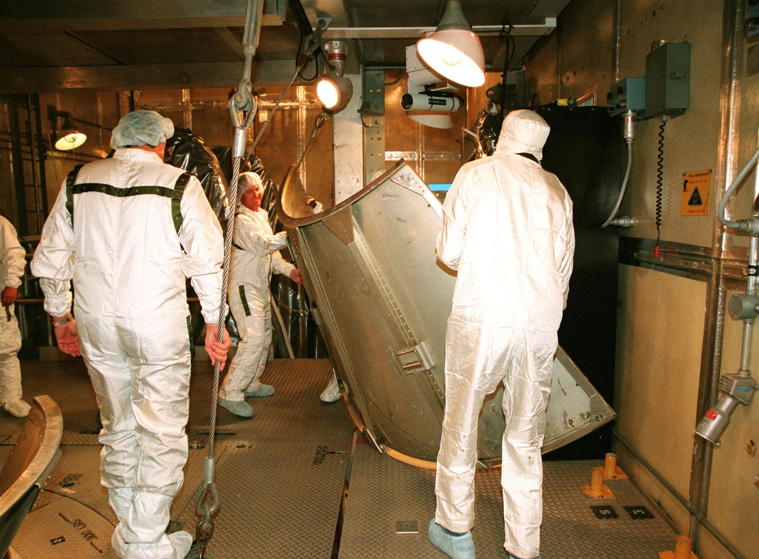 KENNEDY SPACE CENTER, FLA. -- At Launch Complex 17A, Cape Canaveral Air Station, workers place aside a piece of the canister surrounding the Mars Climate Orbiter. Targeted for liftoff on Dec. 10, 1998, aboard a Boeing Delta II (7425) rocket, the orbiter will be the first spacecraft to be launched in the pair of Mars '98 missions. After its arrival at the red planet, the Mars Climate Orbiter will be used primarily to support its companion Mars Polar Lander spacecraft, scheduled for launch on Jan. 3, 1999. The orbiter will then monitor the Martian atmosphere and image the planet's surface on a daily basis for one Martian year, the equivalent of about two Earth years. The spacecraft will observe the appearance and movement of atmospheric dust and water vapor, and characterize seasonal changes on the planet's surface