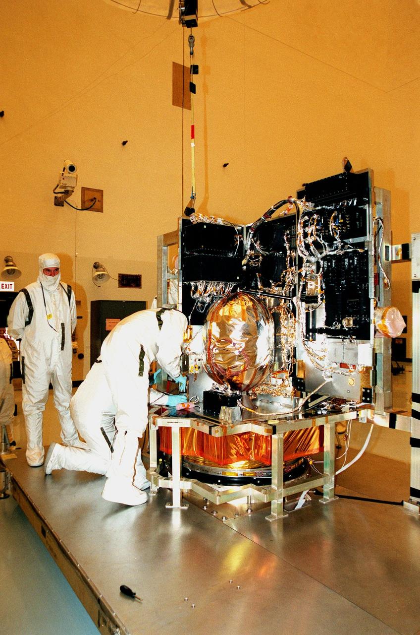 In the Payload Hazardous Servicing Facility, workers get ready to install a science panel on the spacecraft Stardust. Scheduled to be launched aboard a Boeing Delta 7426 rocket from Complex 17, Cape Canaveral Air Station, on Feb. 6, 1999, Stardust will use a unique medium called aerogel to capture comet particles flying off the nucleus of comet Wild 2 in January 2004, plus collect interstellar dust for later analysis. The collected samples will return to Earth in a re-entry capsule to be jettisoned as it swings by Earth in January 2006
