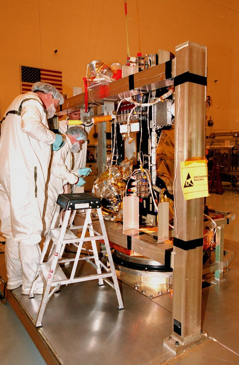 In the Payload Hazardous Servicing Facility, workers install a science panel on the spacecraft Stardust. Scheduled to be launched aboard a Boeing Delta 7426 rocket from Complex 17, Cape Canaveral Air Station, on Feb. 6, 1999, Stardust will use a unique medium called aerogel to capture comet particles flying off the nucleus of comet Wild 2 in January 2004, plus collect interstellar dust for later analysis. The collected samples will return to Earth in a re-entry capsule to be jettisoned as it swings by Earth in January 2006