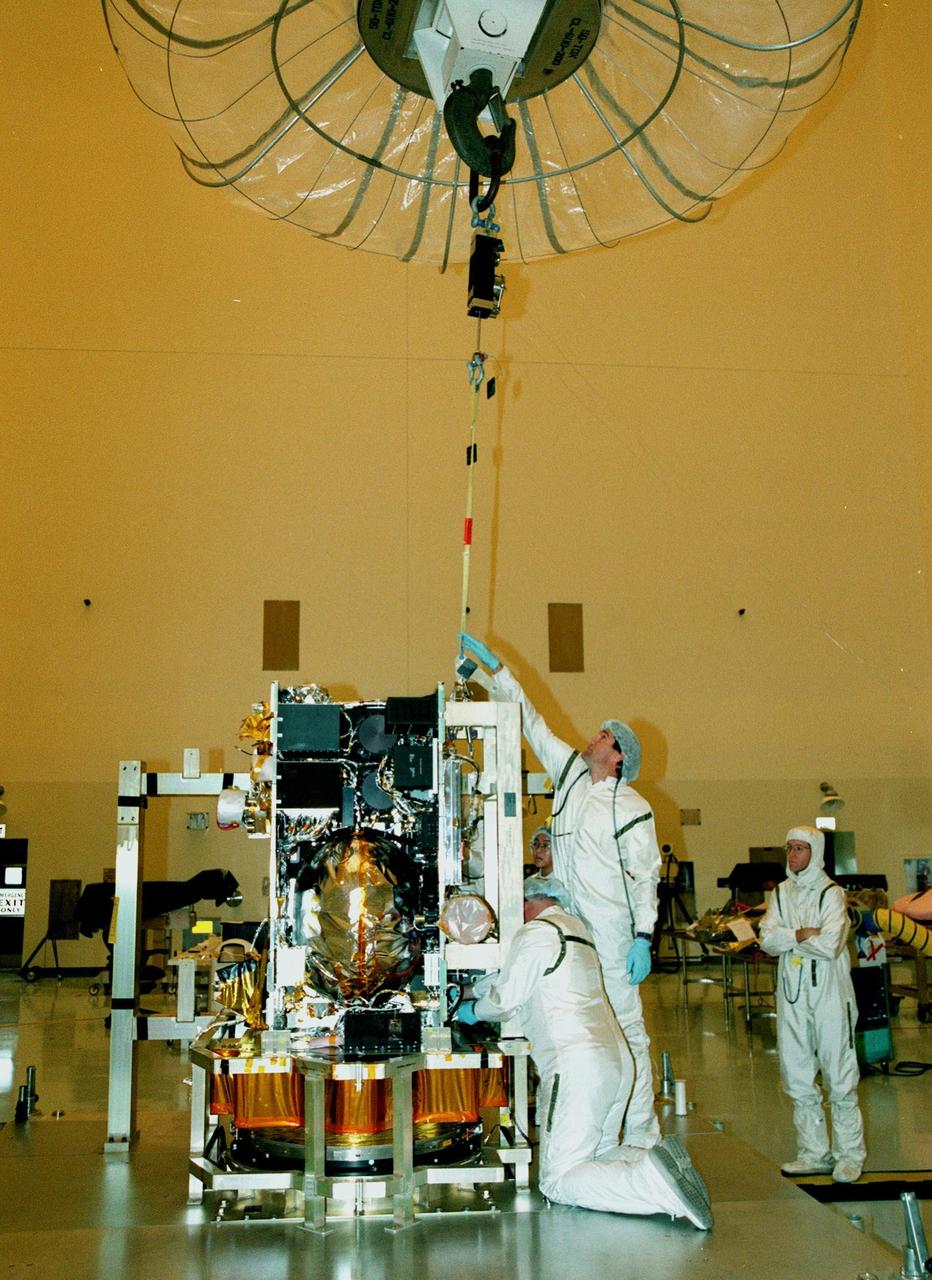 In the Payload Hazardous Servicing Facility, workers adjust a science panel they are installing on the spacecraft Stardust. Scheduled to be launched aboard a Boeing Delta 7426 rocket from Complex 17, Cape Canaveral Air Station, on Feb. 6, 1999, Stardust will use a unique medium called aerogel to capture comet particles flying off the nucleus of comet Wild 2 in January 2004, plus collect interstellar dust for later analysis. The collected samples will return to Earth in a re-entry capsule to be jettisoned as it swings by Earth in January 2006