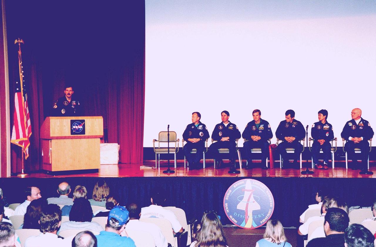 In the Kennedy Space Center (KSC) Training Auditorium, STS-95 Commander Curtis L. Brown Jr. (at podium) addresses KSC employees who were invited to hear the STS-95 crew describe their experiences during their successful mission dedicated to microgravity research and to view a videotape of the highlights of the mission. The other STS-95 crew members are (seated, from left to right) Pilot Steven W. Lindsey; Mission Specialist and Payload Commander Stephen K. Robinson; Mission Specialists Scott E. Parazynski and Pedro Duque, with the European Space Agency (ESA); and Payload Specialists Chiaki Mukai, with the National Space Development Agency of Japan (NASDA), and John H. Glenn Jr., a senator from Ohio and one of the original seven Project Mercury astronauts. Later in the afternoon, the crew will participate in a parade down State Road A1A in nearby Cocoa Beach, reminiscent of those held after missions during the Mercury Program