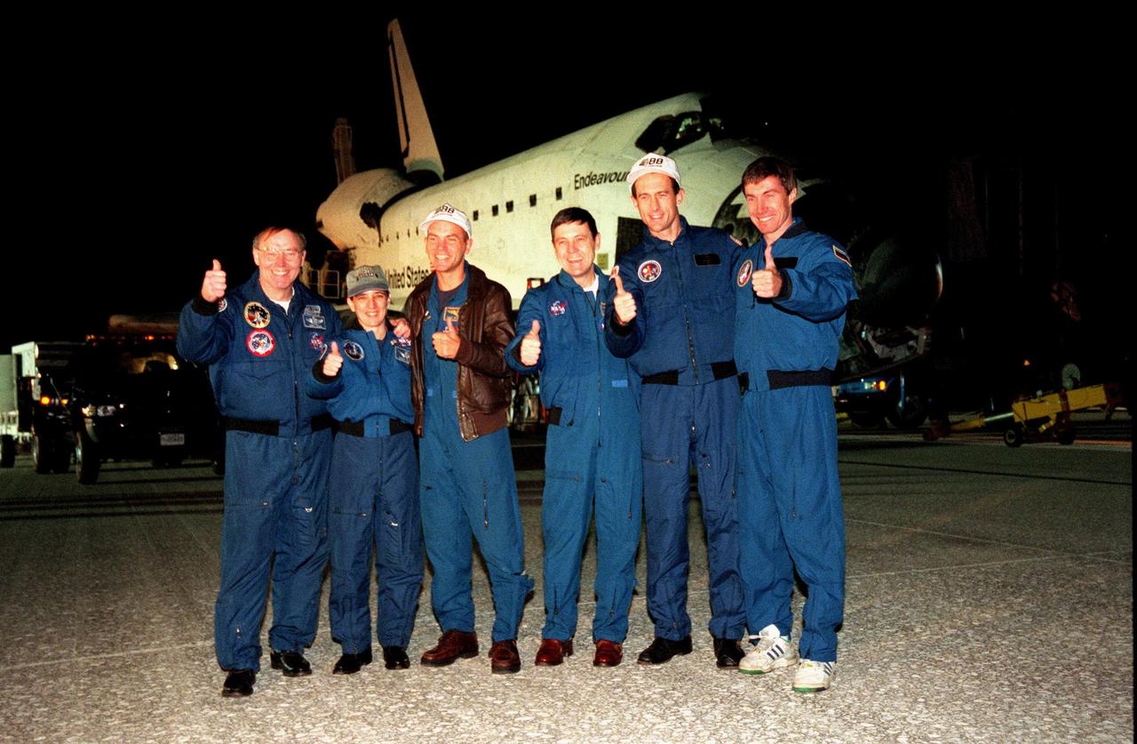 The STS-88 crew, in front of the orbiter Endeavour on Runway 15 of the Shuttle Landing Facility, show their joy at their successful mission with a thumbs up for media gathered nearby. From left, they are Mission Specialists Jerry L. Ross and Nancy J. Currie, Pilot Frederick W. "Rick" Sturckow, Commander Robert D. Cabana, and Mission Specialists James H. Newman and Sergei Konstantinovich Krikalev, a Russian cosmonaut. Endeavour touched down at 10:53:29 p.m. EST after a nearly 12-day, flawless mission. On the 4.6-million-mile mission, Endeavour carried the U.S.-built Unity connecting module to begin construction of the International Space Station. The crew successfully mated Unity with the Russian-built Zarya control module during three space walks. With this mission, Ross completed seven space walks totaling 44 hours and 9 minutes, more than any other American space walker. Newman moved into third place for U.S. space walks with a total of 28 hours and 27 minutes on four excursions