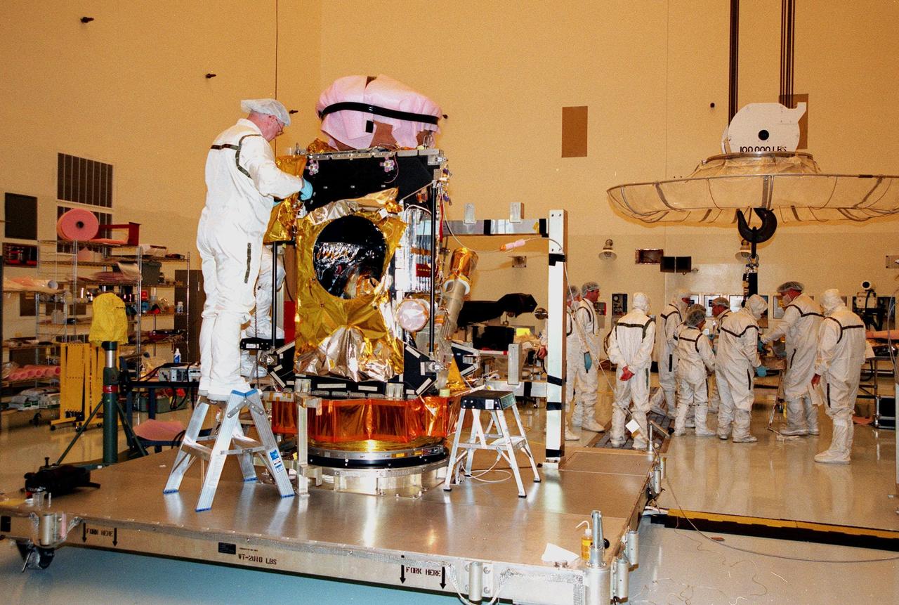 In the Payload Hazardous Servicing Facility, workers oversee closeout operations of the Stardust Sample Return Capsule (SRC) and -X spacecraft panel with the spacecraft bus. Stardust will use a unique medium called aerogel to capture comet particles flying off the nucleus of comet Wild 2 in January 2004, plus collect interstellar dust for later analysis. The collected samples will return to Earth in the SRC to be jettisoned as it swings by Earth in January 2006. Stardust is scheduled to be launched aboard a Boeing Delta 7426 rocket from Complex 17, Cape Canaveral Air Station, on Feb. 6, 1999