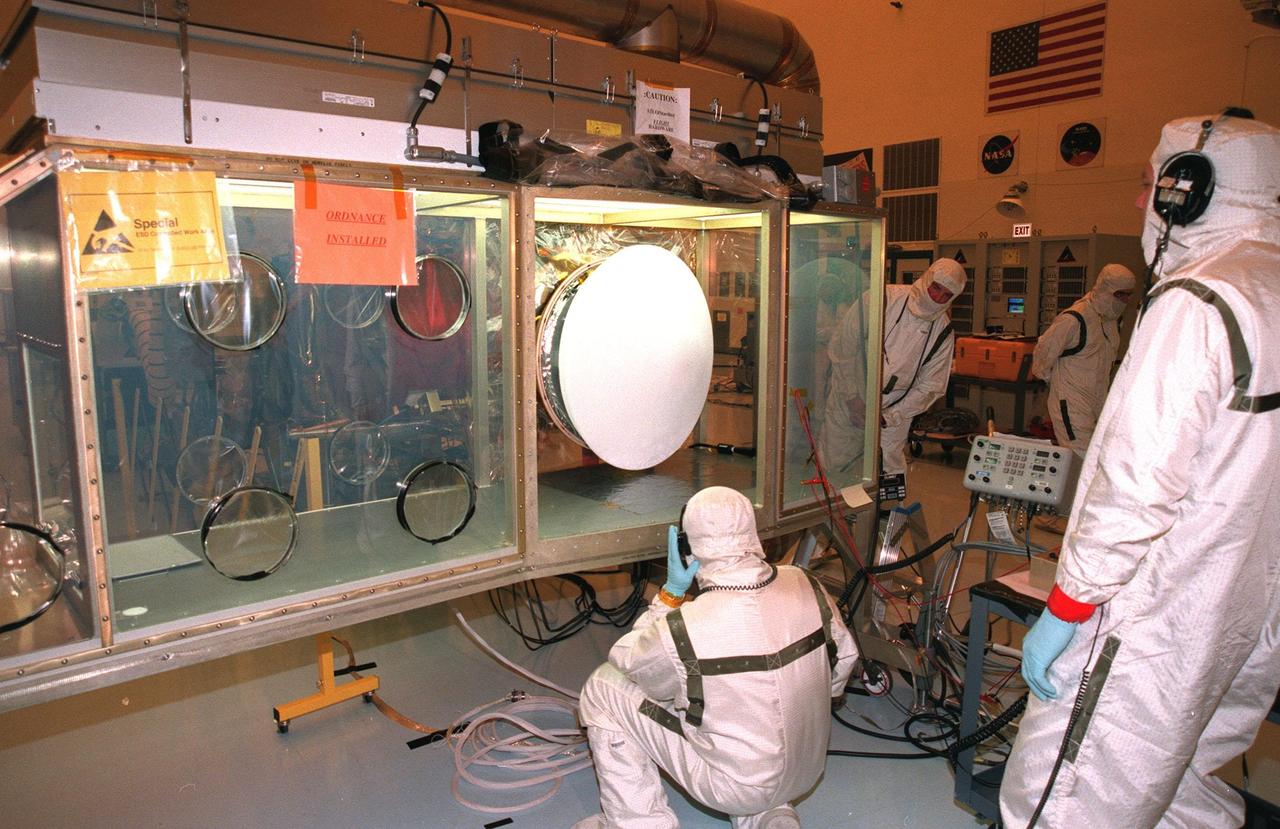 In the Payload Hazardous Servicing Facility, workers prepare to open the Stardust Sample Return Capsule (SRC) residing in a Class 100 glove box. Stardust will use a unique medium called aerogel to capture comet particles flying off the nucleus of comet Wild 2 in January 2004, plus collect interstellar dust for later analysis. The collected samples will return to Earth in the SRC to be jettisoned as it swings by Earth in January 2006. Stardust is scheduled to be launched aboard a Boeing Delta 7426 rocket from Complex 17, Cape Canaveral Air Station, on Feb. 6, 1999