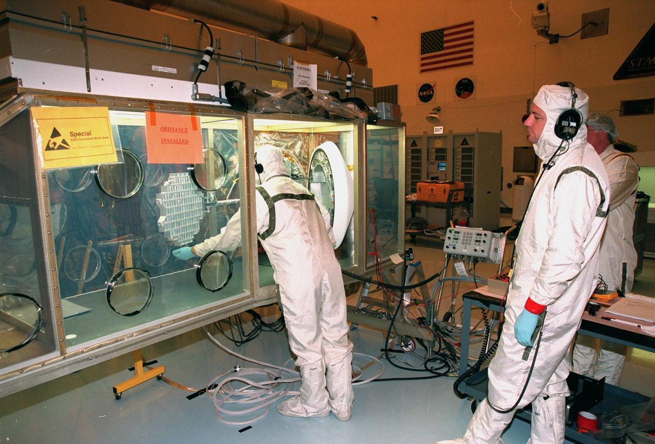 In the Payload Hazardous Servicing Facility, workers inspect the aerogel grid from the Stardust Sample Return Capsule (SRC) to the right of the worker. Stardust will use a unique medium called aerogel to capture comet particles flying off the nucleus of comet Wild 2 in January 2004, plus collect interstellar dust for later analysis. The collected samples will return to Earth in the SRC to be jettisoned as it swings by Earth in January 2006. Stardust is scheduled to be launched aboard a Boeing Delta 7426 rocket from Complex 17, Cape Canaveral Air Station, on Feb. 6, 1999