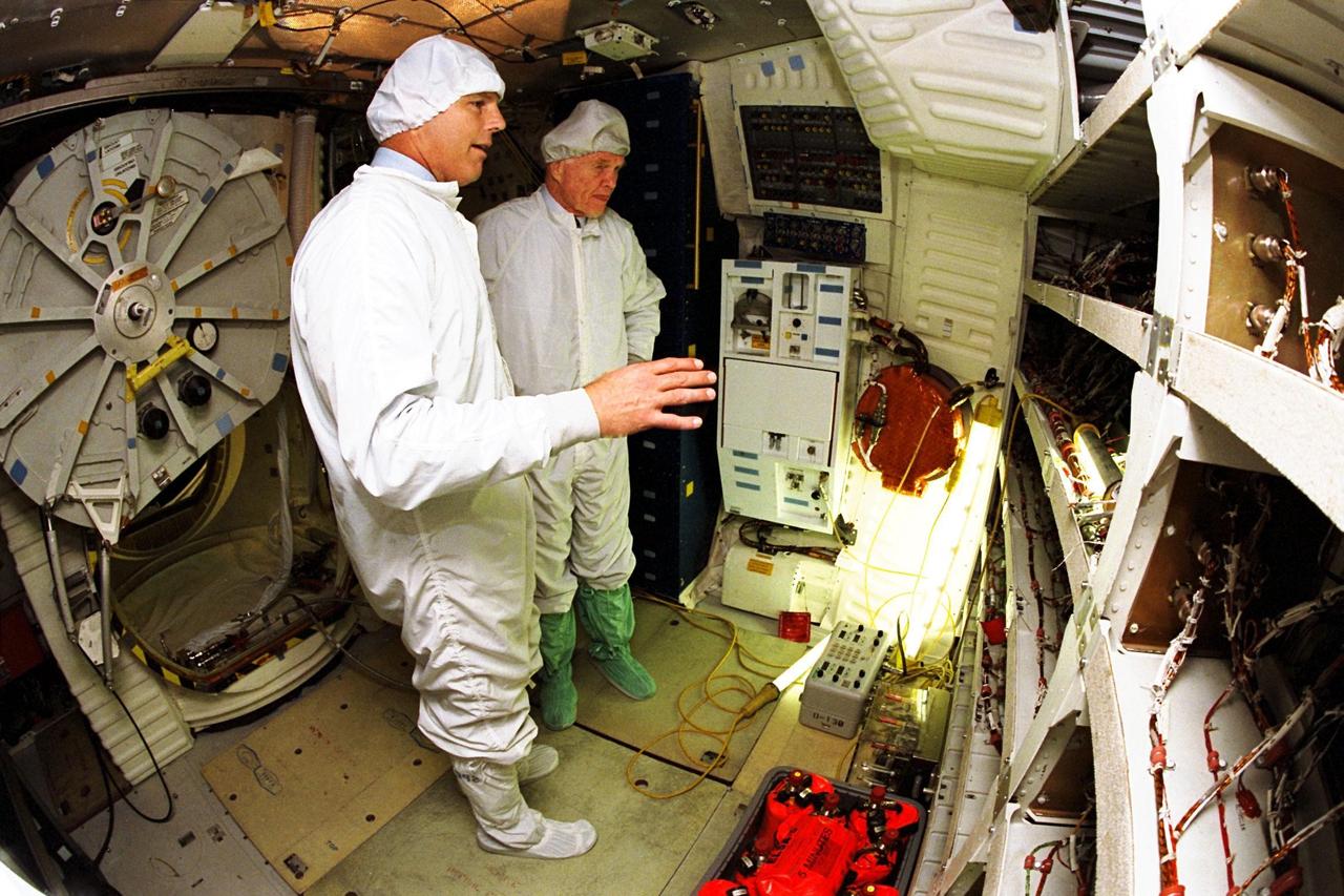 Astronaut Stephen Oswald, at left, explains Shuttle operations to Ohio Senator John Glenn on the orbiter Columbia's middeck at the Orbiter Processing Facility 3 at Kennedy Space Center. Senator Glenn arrived at KSC on Jan. 20 to tour KSC operational areas and to view the launch of STS-89 later this week. Glenn, who made history in 1962 as the first American to orbit the Earth, completing three orbits in a five-hour flight aboard Friendship 7, will fly his second space mission aboard Space Shuttle Discovery this October. Glenn is retiring from the Senate at the end of this year and will be a payload specialist aboard STS-95