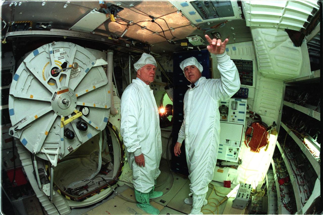 Astronaut Stephen Oswald, at right, explains Shuttle operations to Ohio Senator John Glenn on the orbiter Columbia's middeck at the Orbiter Processing Facility 3 at Kennedy Space Center. Senator Glenn arrived at KSC on Jan. 20 to tour KSC operational areas and to view the launch of STS-89 later this week. Glenn, who made history in 1962 as the first American to orbit the Earth, completing three orbits in a five-hour flight aboard Friendship 7, will fly his second space mission aboard Space Shuttle Discovery this October. Glenn is retiring from the Senate at the end of this year and will be a payload specialist aboard STS-95