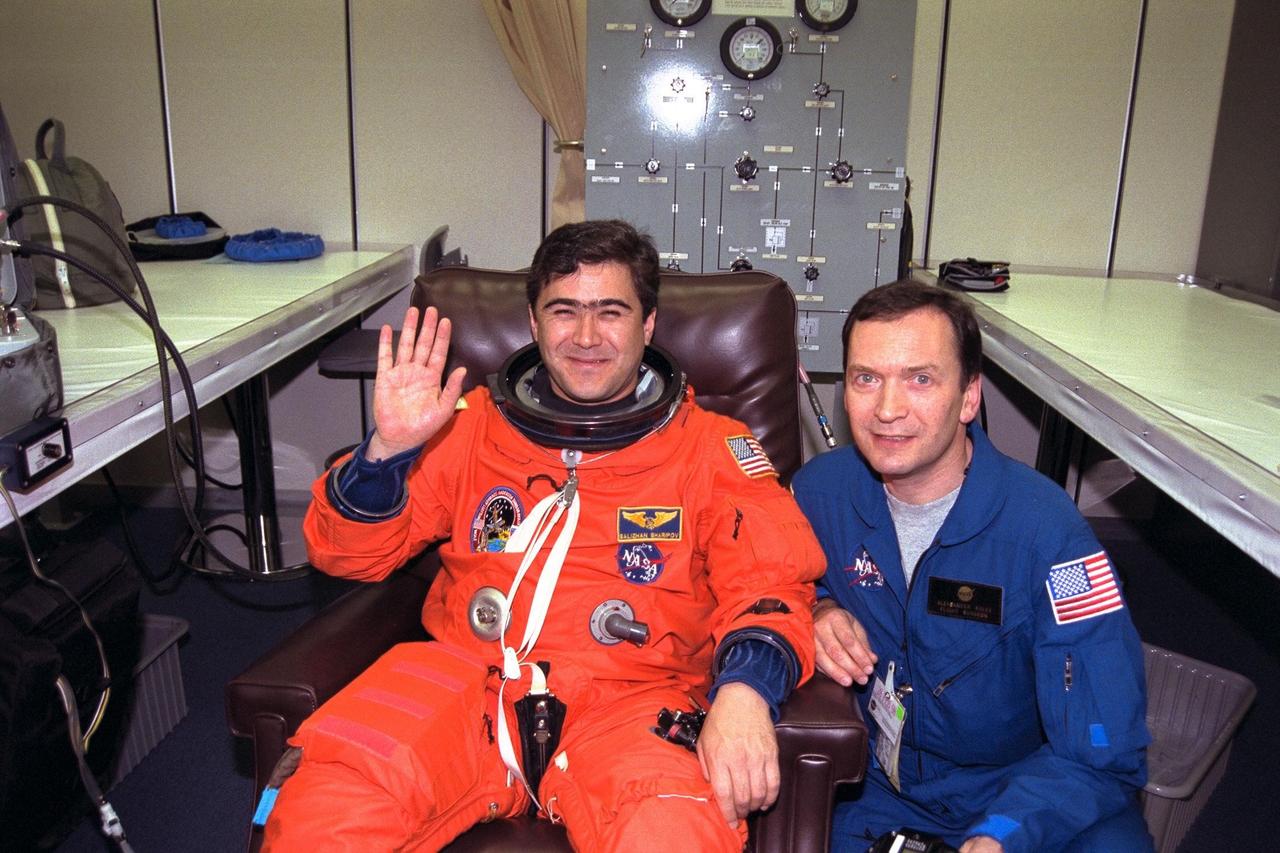 STS-89 Mission Specialist Salizhan Sharipov of the Russian Space Agency, at left, waves as he and his flight surgeon, Alexander Kulev, complete the donning of Sharipov’s launch/entry suit in the Operations and Checkout (O&C) Building. In 1994, Sharipov graduated from Moscow State University with a degree in cartography. He and six fellow crew members will soon depart the O&C and head for Launch Pad 39A, where the Space Shuttle Endeavour will lift off during a launch window that opens at 9:43 p.m. EST, Jan. 22. STS-89 is the eighth of nine planned missions to dock the Space Shuttle with Russia's Mir space station