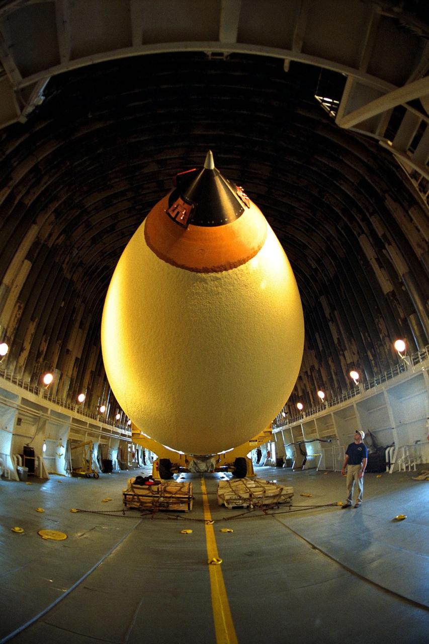 KENNEDY SPACE CENTER, FLA. -- Bren Wade, chief mate of the "Liberty Star," looks up at the Space Shuttle's first super lightweight external tank as it is moved on a barge to Port Canaveral, Fla. The tank is scheduled to undergo processing at Kennedy Space Center for flight on STS-91, targeted for launch in late May. The improved tank is 7,500 pounds lighter than its predecessors and was developed to increase the Shuttle payload capacity on International Space Station assembly flights. From the outside, the new orange-colored tank appears identical to tanks currently used on Shuttle flights. Major changes, however, include the use of new materials and a revised internal design. The new liquid oxygen and liquid hydrogen tanks are constructed of aluminum lithium a lighter, stronger material than the metal alloy currently used. The redesigned walls of the liquid hydrogen tank were machined to provide additional strength and stability as well. This photograph was taken with a wide-angle lens
