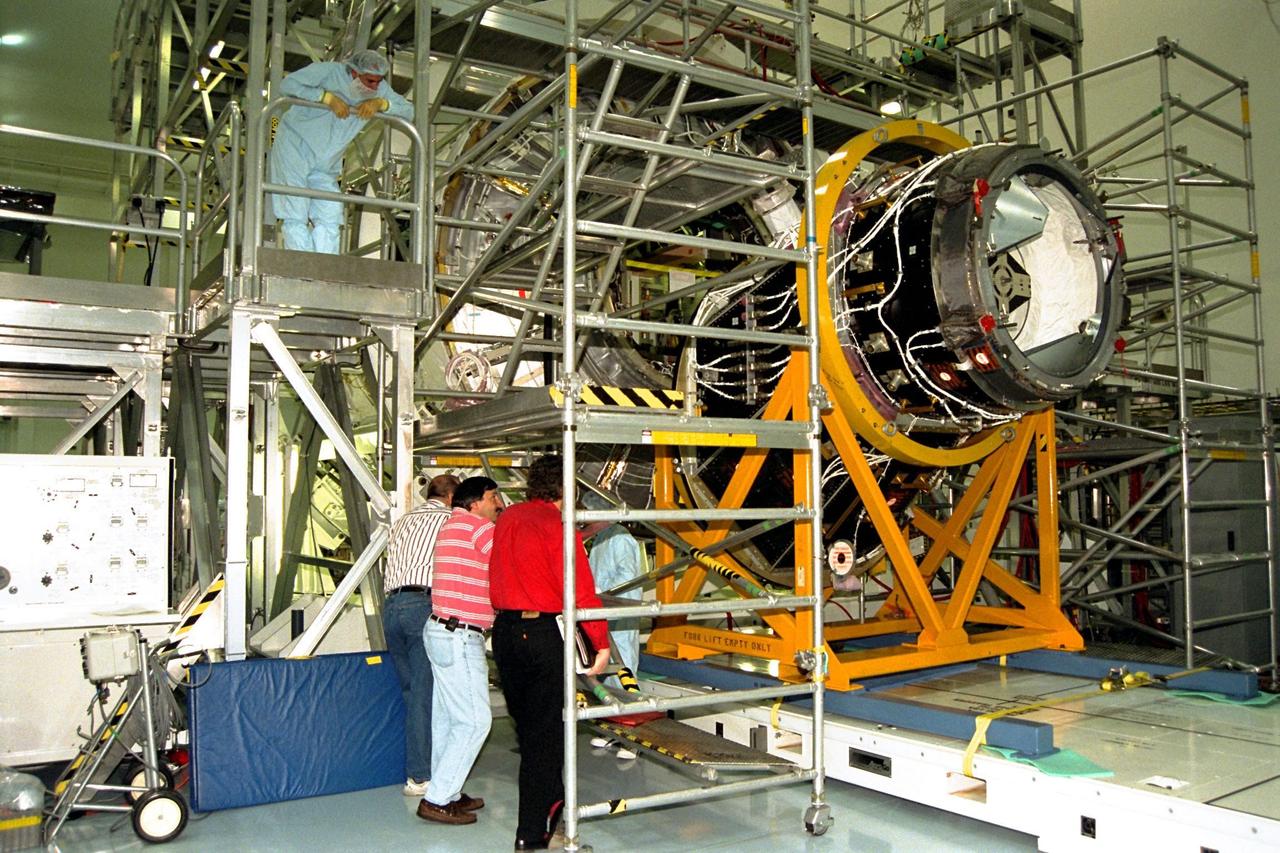 KENNEDY SPACE CENTER, FLA. -- Technicians and workers observe preparations to join the Pressurized Mating Adapter (PMA)-2, seen here in its yellow workstand at right, to Node 1 (the International Space Station’s [ISS] structural building block) in KSC’s Space Station Processing Facility. This PMA is a cone-shaped connector to Node 1, which will have two PMAs attached once PMA-2 is mated with the node. The node (surrounded here by scaffolding) and PMAs, which together will make up the first element of the ISS, are scheduled to be launched aboard the Space Shuttle Endeavour on STS-88