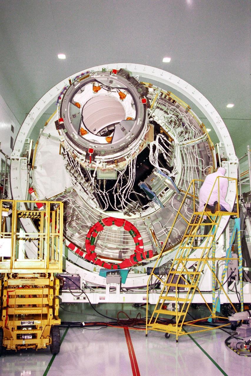 KENNEDY SPACE CENTER, FLA. -- Node 1, the first U.S. element for the International Space Station, and the Pressurized Mating Adapter-1 (PMA-1) continue with prelaunch preparation activities at KSC's Space Station Processing Facility. The node and PMA-1 are seen here on a workstand as a Boeing technician removes cables to get the node ready to be moved the next day to another stand for an interim weight and center of gravity determination. (The final determination is planned to be performed prior to transporting Node 1 to the launch pad.) Upon completing the interim determination, the node and PMA will be hoisted into the Shuttle payload transportation canister and the doors will be closed for a two-week leak check. Node 1 is a connecting passageway to the living and working areas of the space station. Node 1 is scheduled to fly on STS-88
