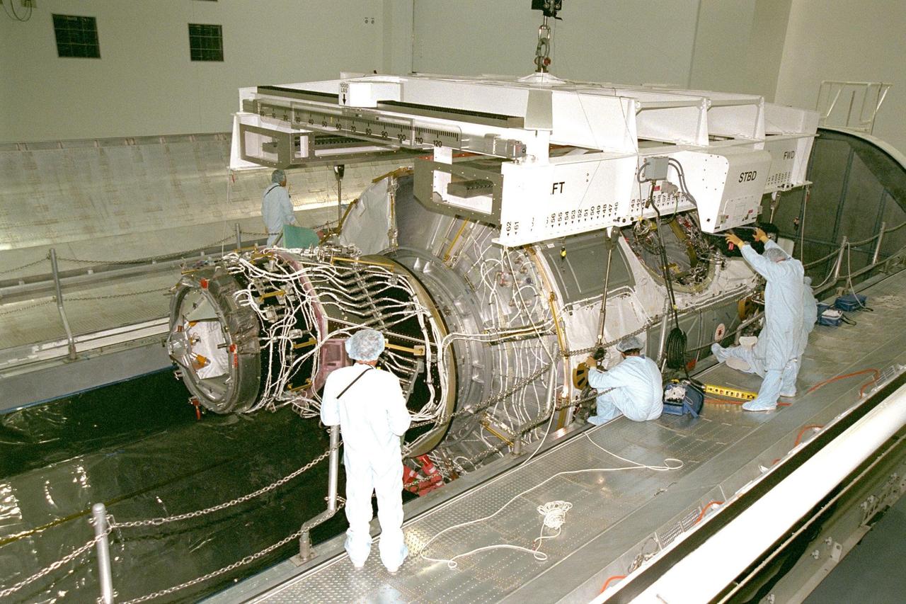 Node 1, the first U.S. element for the International Space Station, and attached Pressurized Mating Adapter-1 (PMA-1) continue with prelaunch preparation activities at KSC's Space Station Processing Facility. Node 1 is a connecting passageway to the living and working areas of the space station. The node and PMA-1 are seen here being moved into the Shuttle payload transportation canister, where the doors will be closed for a two-week leak check. The node and PMA were moved to the canister from the element rotation stand, or test stand, where they underwent an interim weight and center of gravity determination. The final determination is planned to be performed prior to transporting Node 1 to the launch pad. Node 1 is scheduled to fly on STS-88