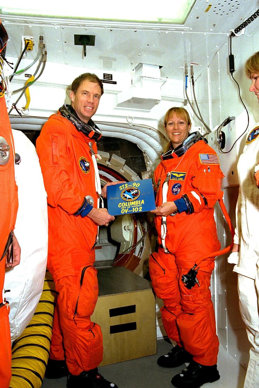 The crew of STS-90 participate in Terminal Countdown Demonstration Test (TCDT) activities at KSC's Launch Pad 39B. The TCDT is held at KSC prior to each Space Shuttle flight to provide crews with the opportunity to participate in simulated countdown activities. Here, STS-90 Commander Richard Searfoss and Mission Specialist Kathryn (Kay) Hire hold the mission patch with orbiter information. Columbia is targeted for launch of STS-90 on April 16 at 2:19 p.m. EDT and will be the second mission of 1998. The mission is scheduled to last nearly 17 days