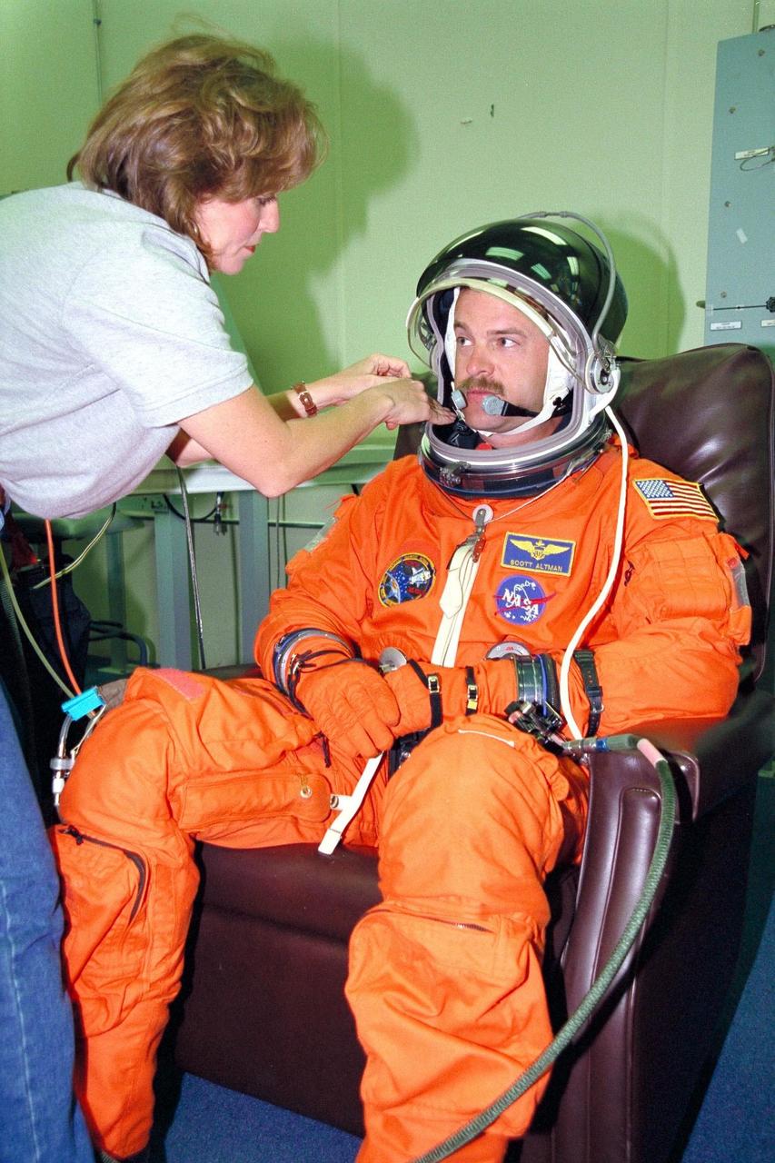 KENNEDY SPACE CENTER, FLA. -- STS-90 Pilot Scott Altman is assisted during suit-up activities by Lockheed Suit Technician Valerie McNeil from Johnson Space Center in KSC's Operations and Checkout Building. Altman and the rest of the STS-90 crew will shortly depart for Launch Pad 39B, where the Space Shuttle Columbia awaits a second liftoff attempt at 2:19 p.m. EDT. His first trip into space, Altman is participating in a life sciences research flight that will focus on the most complex and least understood part of the human body the nervous system. Neurolab will examine the effects of spaceflight on the brain, spinal cord, peripheral nerves and sensory organs in the human body