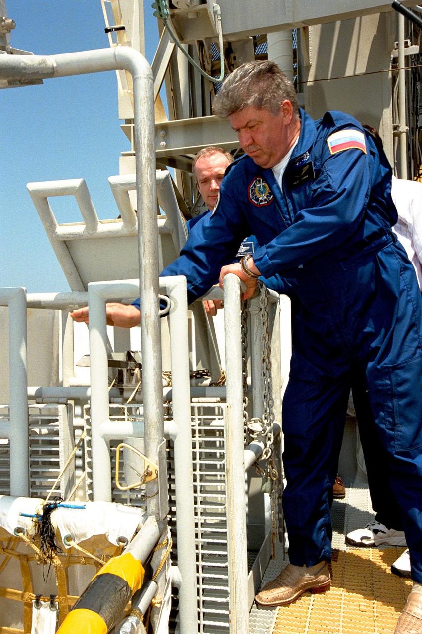 KENNEDY SPACE CENTER,  Fla. -- STS-91 Mission Specialist Valery Ryumin, with the Russian Space Agency, reaches for a lever which releases a slidewire basket as Mission Commander Charles Precourt looks on during Terminal Countdown Demonstration Test (TCDT) training activities at the 195-foot level of Launch Complex 39A. The crew is practicing emergency egress procedures during the TCDT, a dress rehearsal for launch. STS-91 is scheduled to be launched on June 2 with a launch window opening around 6:10 p.m. EDT. The mission will feature the ninth Shuttle docking with the Russian Space Station Mir, the first Mir docking for Discovery, the conclusion of Phase I of the joint U.S.-Russian International Space Station Program, and the first flight of the new Space Shuttle super lightweight external tank. The STS-91 flight crew also includes Pilot Dominic Gorie and Mission Specialists Wendy B. Lawrence; Franklin Chang-Diaz, Ph.D.; and Janet Kavandi, Ph.D. Andrew Thomas, Ph.D., will be returning to Earth with the crew after living more than four months aboard Mir