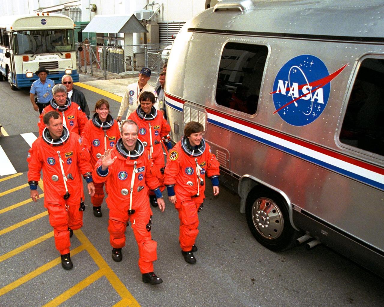 The STS-91 crew participates in a simulated walk-out from the Operations and Checkout Building to board a van which will take them to Launch Complex 39A during Terminal Countdown Demonstration Test (TCDT) activities. The TCDT is a dress rehearsal for launch and ends with a mock launch countdown culminating in a simulated main engine cut-off. From left to right, the crew members are (front row) Pilot Dominic Gorie; Mission Commander Charles Precourt (waving); and Mission Specialist Wendy B. Lawrence; and (back row) Mission Specialists Valery Ryumin, with the Russian Space Agency; Janet Kavandi, Ph.D.; and Franklin Chang-Diaz, Ph.D. STS-91 is scheduled to be launched on June 2 with a launch window opening around 6:10 p.m. EDT. The mission will feature the ninth Shuttle docking with the Russian Space Station Mir, the first Mir docking for Discovery, the conclusion of Phase I of the joint U.S.-Russian International Space Station Program, and the first flight of the new Space Shuttle super lightweight external tank. Andrew Thomas, Ph.D., will be returning to Earth with the crew after living more than four months aboard Mir