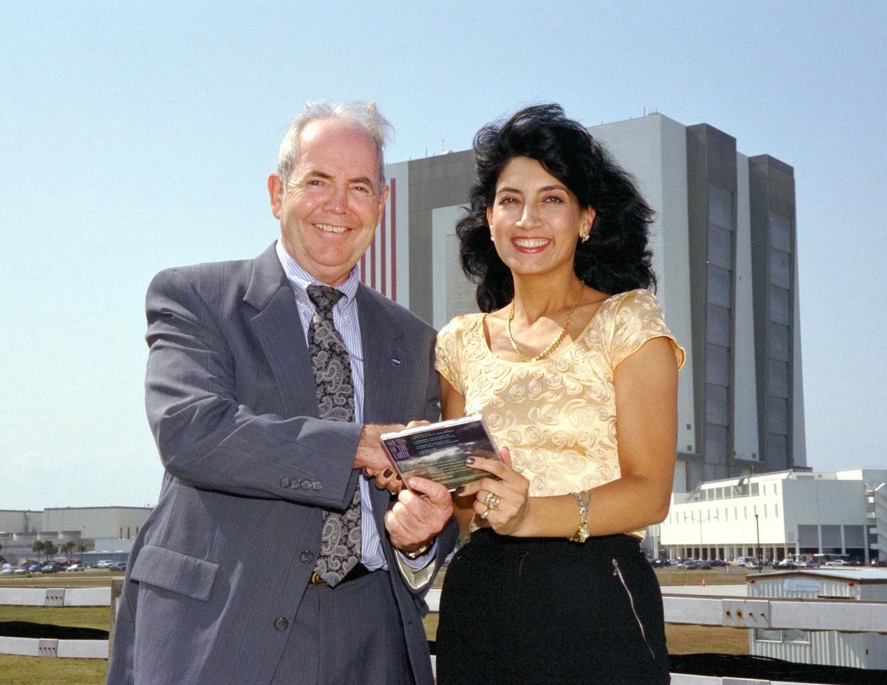 KENNEDY SPACE CENTER, FLA. -- David Dickinson, the acting director of the National Aeronautics and Space Administration (NASA) Public Affairs Office at Kennedy Space Center, accepts a copy of Bulgarian singer Dyana Dafova's latest compact disc (CD) from her on behalf of NASA. The 525-foot tall Vehicle Assembly Building, where Space Shuttle orbiters are mated to their external tank/solid rocket booster stacks, looms in the background. Dyana is touring the United States to promote her CD, entitled "Sounds of the Earth," and was an invited guest of NASA for the launch of Columbia on STS-90, the Neurolab mission, earlier in the day. Columbia lifted off from Launch Pad 39B at 2:19 p.m. EDT. Dyana characterized the music on her CD as a new sound, incorporating jazz and new age classics, sung in a newly created language comprised of Bulgarian, English, Sanskrit, Aramski and Hebrew