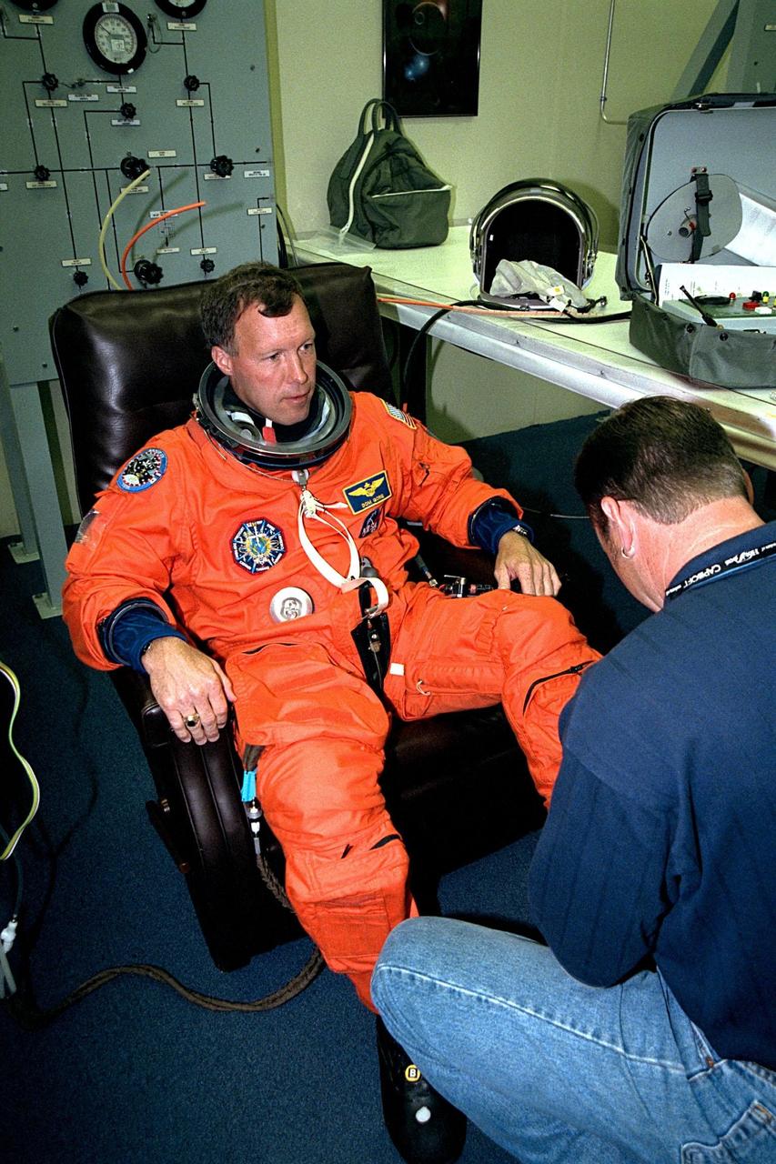 With the help of a suit technician, STS-91 Pilot Dominic L. Gorie dons his flight suit in the Operations and Checkout (O&C) Building prior to the crew walkout and transport to Launch Pad 39A. Gorie is on his first Shuttle mission. As a commander in the Navy, he flew combat missions in Operation Desert Storm and has earned a Distinguished Flying Cross as well as a master’s degree in aviation systems. Along with backing up Precourt on the flight deck, Gorie will perform the final Shuttle-Mir undocking and flyaround. He will also assist with the transfer of materials to and from Mir and the photographic documentation of the space station. STS91 is scheduled to be launched on June 2 with a launch window opening around 6:10 p.m. EDT. The mission will feature the ninth and final Shuttle docking with the Russian space station Mir, the first Mir docking for Discovery, the first on-orbit test of the Alpha Magnetic Spectrometer (AMS), and the first flight of the new Space Shuttle super lightweight external tank. Astronaut Andrew S. W. Thomas will be returning to Earth as a STS-91 crew member after living more than four months aboard Mir