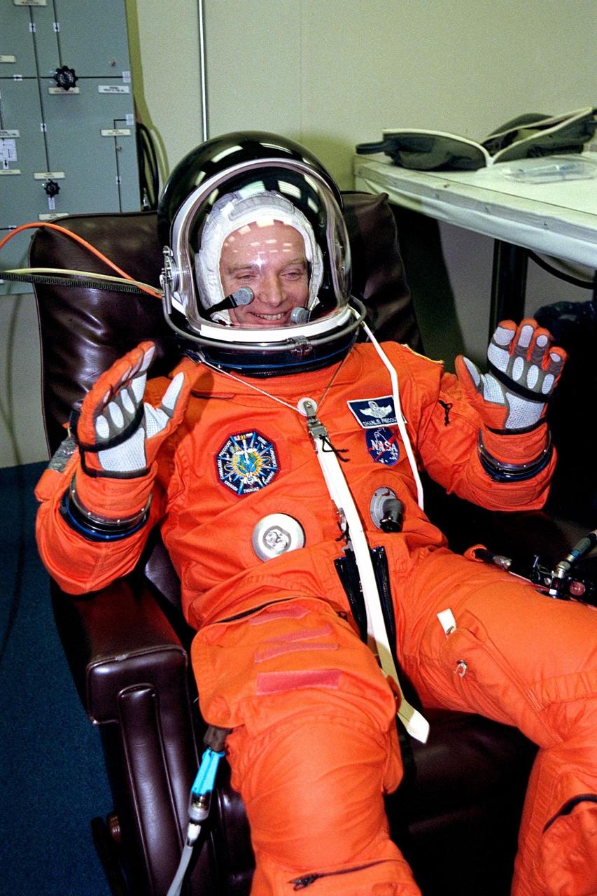 STS-91 Mission Commander Charles J. Precourt holds his arms up and smiles during the final checkout of his flight suit in the Operations and Checkout (O&C) Building. The test is conducted prior to the crew walkout and transport to Launch Pad 39A. He is on his fourth space flight and third trip to Mir. Precourt is a colonel in the Air Force and has more than 6,500 hours of flight experience in more than 50 types of civil and military aircraft. He will have overall responsibility for the mission and will perform the final docking with the Russian space station. STS-91 is scheduled to be launched on June 2 with a launch window opening around 6:10 p.m. EDT. The mission will feature the ninth and final Shuttle docking with the Russian space station Mir, the first Mir docking for Discovery, the first on-orbit test of the Alpha Magnetic Spectrometer (AMS), and the first flight of the new Space Shuttle super lightweight external tank. Astronaut Andrew S. W. Thomas will be returning to Earth as a STS-91 crew member after living more than four months aboard Mir