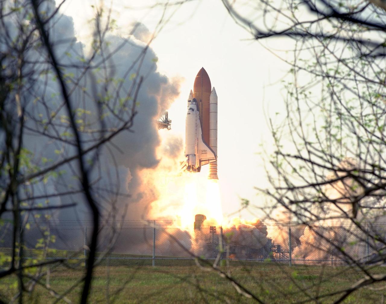 KENNEDY SPACE CENTER,  Fla. -- Tree branches frame the Space Shuttle Discovery as it lifts off from Launch Pad 39A at 6:06:24 p.m. EDT June 2 on its way to the Mir space station. On board Discovery are Mission Commander Charles J. Precourt; Pilot Dominic L. Gorie; and Mission Specialists Wendy B. Lawrence, Franklin R. Chang-Diaz, Janet Lynn Kavandi and Valery Victorovitch Ryumin. The nearly 10-day mission will feature the ninth and final Shuttle docking with the Russian space station Mir, the first Mir docking for the Space Shuttle orbiter Discovery, the first on-orbit test of the Alpha Magnetic Spectrometer (AMS), and the first flight of the new Space Shuttle super lightweight external tank. Astronaut Andrew S. W. Thomas will be returning to Earth as an STS-91 crew member after living more than four months aboard Mir