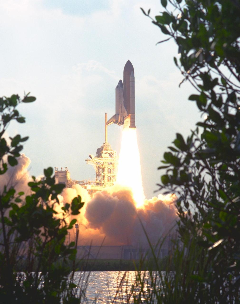 KENNEDY SPACE CENTER,  Fla. -- The Space Coast's natural foliage frames the Space Shuttle Discovery and the reflection of the intense heat and light of its liftoff from Launch Pad 39A at 6:06:24 p.m. EDT June 2. On board Discovery are Mission Commander Charles J. Precourt; Pilot Dominic L. Gorie; and Mission Specialists Wendy B. Lawrence, Franklin R. Chang-Diaz, Janet Lynn Kavandi and Valery Victorovitch Ryumin. The nearly 10-day mission will feature the ninth and final Shuttle docking with the Russian space station Mir, the first Mir docking for the Space Shuttle orbiter Discovery, the first on-orbit test of the Alpha Magnetic Spectrometer (AMS), and the first flight of the new Space Shuttle super lightweight external tank. Astronaut Andrew S. W. Thomas will be returning to Earth as an STS-91 crew member after living more than four months aboard Mir