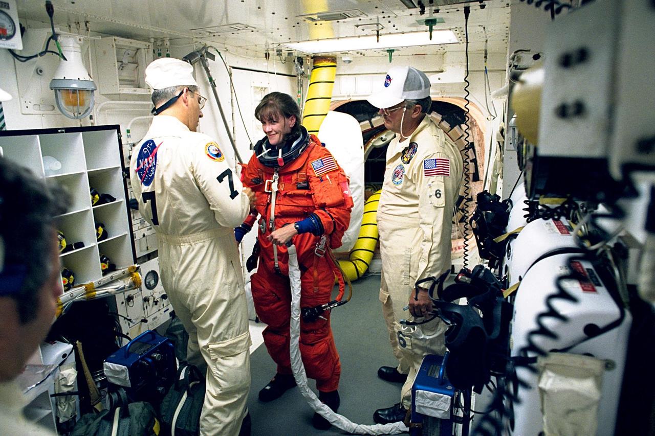STS-91 Mission Specialist Janet Lynn Kavandi gets some help with her flight suit from David Brandt in the White Room at Launch Pad 39A. He and white room crew member Greg Lohning will assist Kavandi to enter the Space Shuttle Discovery through the hatch seen in the background