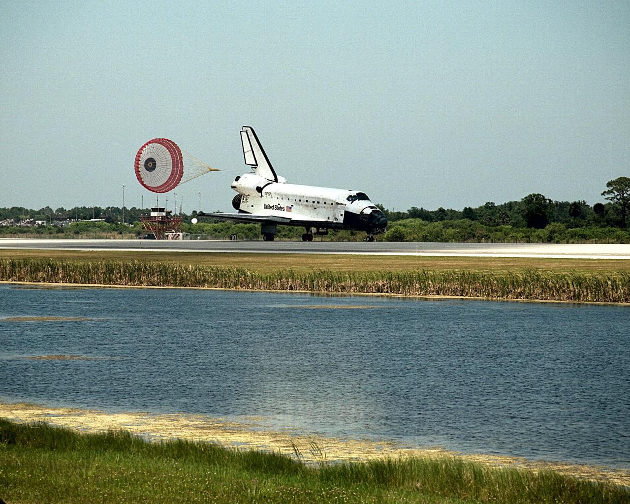 KENNEDY SPACE CENTER, FLA. -- With KSC's Shuttle Landing Facility control tower and the NASA Public Affairs midfield press site as backdrop, the orbiter Discovery's drag chute deploys as it lands on Runway 15 to complete the STS-91 mission. Main gear touchdown was at 2:00:18 p.m. EDT on June 12, 1998, landing on orbit 155 of the mission. The wheels stopped at 2:01:22 p.m. EDT, for a total mission-elapsed time of 9 days, 19 hours, 55 minutes and 1 second. The 91st Shuttle mission was the 44th KSC landing in the history of the Space Shuttle program and the 15th consecutive landing at KSC. During the mission, the orbiter docked with the Russian space station Mir for the ninth time, concluding Phase I of the joint U.S.-Russian International Space Station Program. STS-91 also featured first flights for both the Alpha Magnetic Spectrometer and the Space Shuttle super lightweight external tank. The STS-91 flight crew included Mission Commander Charles J. Precourt; Pilot Dominic L. Gorie; and Mission Specialists Wendy B. Lawrence, Franklin R. Chang-Diaz, Janet Lynn Kavandi and Valery Victorovitch Ryumin of the Russian Space Agency. Astronaut Andrew S. W. Thomas also returned to Earth as an STS-91 crew member after 141 days in space