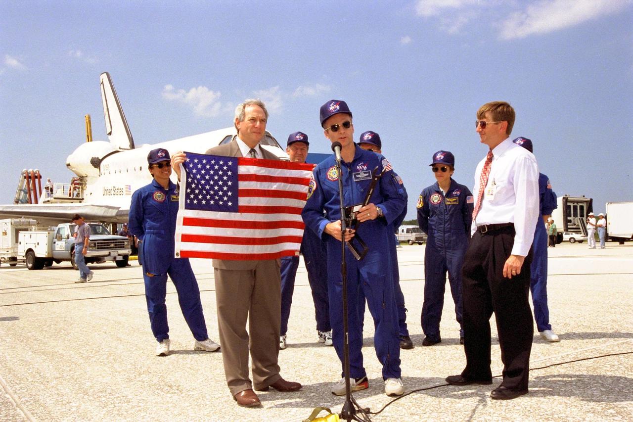 STS-91 Mission Commander Charles J. Precourt (at microphone) presents an American flag, a special wrench, and an optical disc to NASA Administrator Dan Goldin following Discovery's landing at KSC's Shuttle Landing Facility, as Phase I Shuttle/Mir Program Manager Frank Culbertson and the other members of the STS-91 flight crew look on. This landing not only concluded the STS-91 mission, but Phase I of the joint U.S.-Russian International Space Station Program as well. The flag rode aboard Mir from the beginning of the Phase I program, the wrench was used on Mir and will be used on the International Space Station, and the optical disc holds data recorded on Mir. All of these items were brought back to Earth from Mir by the STS-91 crew. Discovery's main gear touchdown on Runway 15 was at 2:00:18 p.m. EDT on June 12, 1998, on orbit 155 of the mission. The wheels stopped at 2:01:22 p.m. EDT, for a total mission-elapsed time of 9 days, 19 hours, 55 minutes and 1 second. The 91st Shuttle mission was the 44th KSC landing in the history of the Space Shuttle program and the 15th consecutive landing at KSC. Besides Commander Precourt, the STS-91 flight crew also included Pilot Dominic L. Gorie and Mission Specialists Wendy B. Lawrence, Franklin R. Chang-Diaz, Janet Lynn Kavandi and Valery Victorovitch Ryumin of the Russian Space Agency. Astronaut Andrew S. W. Thomas also returned to Earth from Mir as an STS-91 crew member after 141 days in space