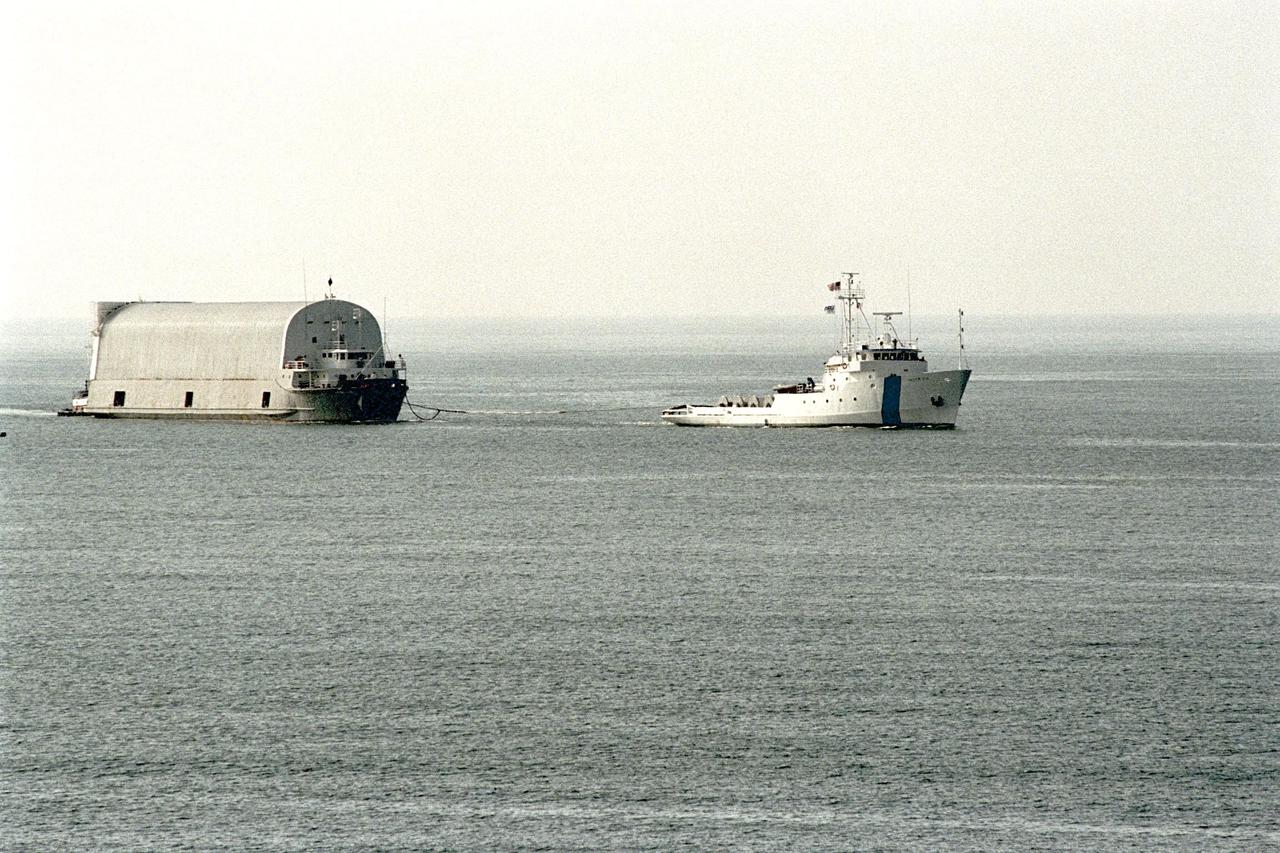 KENNEDY SPACE CENTER, FLA. -- Freedom Star, one of NASA's two solid rocket booster recovery ships, tows a barge containing the third Space Shuttle super lightweight external tank (SLWT) into Port Canaveral. This SLWT will be used to launch the orbiter Discovery on mission STS-95 in October. This first-time towing arrangement, part of a cost savings plan by NASA to prudently manage existing resources, began June 12 from the Michoud Assembly Facility in New Orleans where the Shuttle's external tanks are manufactured. The barge will now be transported up the Banana River to the LC-39 turn basin using a conventional tugboat. Previously, NASA relied on an outside contractor to provide external tank towing services at a cost of about $120,000 per trip. The new plan allows NASA's Space Flight Operations contractor, United Space Alliance (USA), to provide the same service directly to NASA using the recovery ships during their downtime between Shuttle launches. Studies show a potential savings of about $50,000 per trip. The cost of the necessary ship modifications should be paid back by the fourteenth tank delivery. The other recovery ship, Liberty Star, has also undergone deck strengthening enhancements and will soon have the necessary towing winch installed. The other recovery vessel, Liberty Star, has undergone deck strengthening enhancements along with Freedom Star and will soon have the necessary towing winch installed