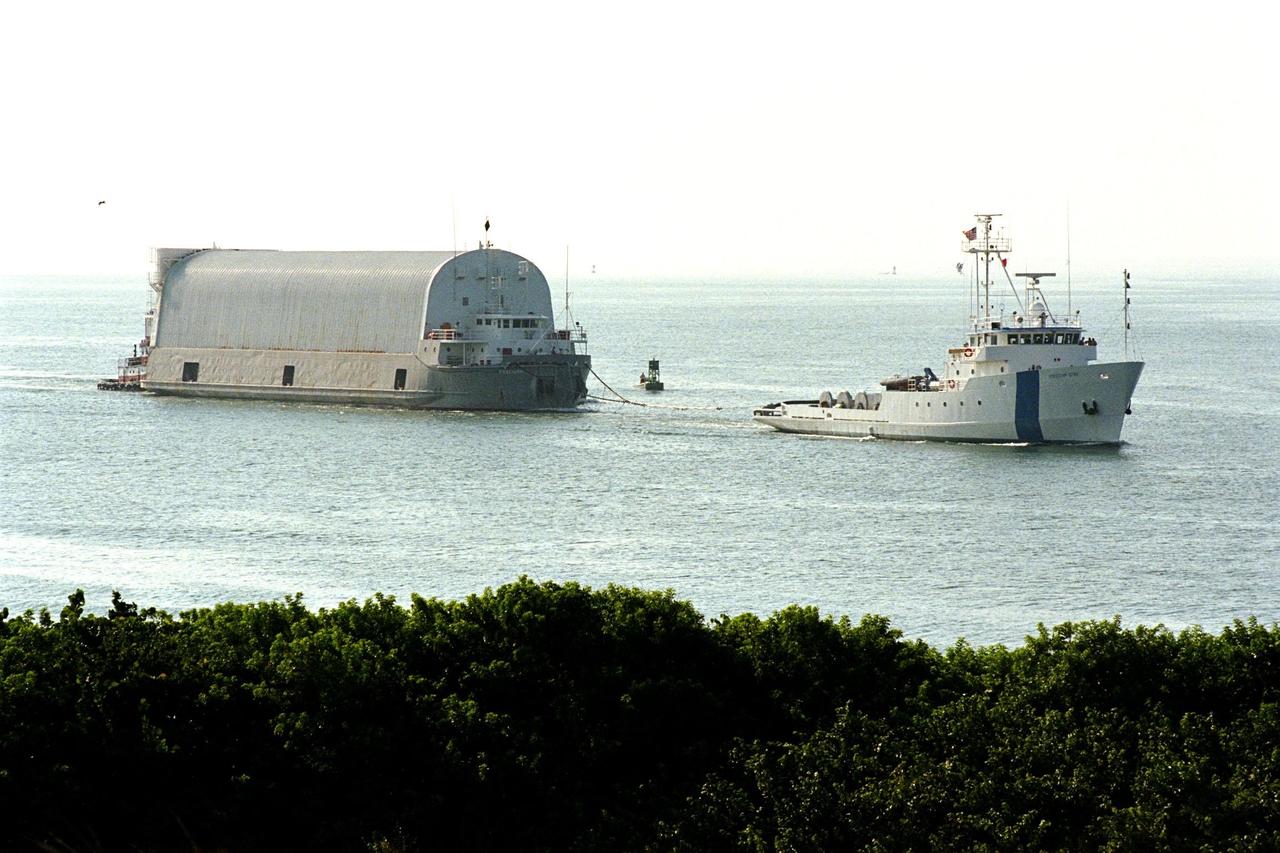 KENNEDY SPACE CENTER, FLA. -- Freedom Star, one of NASA's two solid rocket booster recovery ships, tows a barge containing the third Space Shuttle super lightweight external tank (SLWT) into Port Canaveral. This SLWT will be used to launch the orbiter Discovery on mission STS-95 in October. This first-time towing arrangement, part of a cost savings plan by NASA to prudently manage existing resources, began June 12 from the Michoud Assembly Facility in New Orleans where the Shuttle's external tanks are manufactured. The barge will now be transported up the Banana River to the LC-39 turn basin using a conventional tugboat. Previously, NASA relied on an outside contractor to provide external tank towing services at a cost of about $120,000 per trip. The new plan allows NASA's Space Flight Operations contractor, United Space Alliance (USA), to provide the same service directly to NASA using the recovery ships during their downtime between Shuttle launches. Studies show a potential savings of about $50,000 per trip. The cost of the necessary ship modifications should be paid back by the fourteenth tank delivery. The other recovery ship, Liberty Star, has also undergone deck strengthening enhancements and will soon have the necessary towing winch installed. 