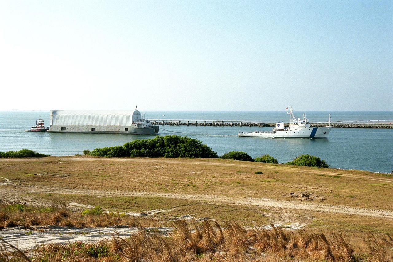 KENNEDY SPACE CENTER, FLA. -- Freedom Star, one of NASA's two solid rocket booster recovery ships, tows a barge containing the third Space Shuttle super lightweight external tank (SLWT) into Port Canaveral. This SLWT will be used to launch the orbiter Discovery on mission STS-95 in October. This first-time towing arrangement, part of a cost savings plan by NASA to prudently manage existing resources, began June 12 from the Michoud Assembly Facility in New Orleans where the Shuttle's external tanks are manufactured. The barge will now be transported up the Banana River to the LC-39 turn basin using a conventional tugboat. Previously, NASA relied on an outside contractor to provide external tank towing services at a cost of about $120,000 per trip. The new plan allows NASA's Space Flight Operations contractor, United Space Alliance (USA), to provide the same service directly to NASA using the recovery ships during their downtime between Shuttle launches. Studies show a potential savings of about $50,000 per trip. The cost of the necessary ship modifications should be paid back by the fourteenth tank delivery. The other recovery ship, Liberty Star, has also undergone deck strengthening enhancements and will soon have the necessary towing winch installed