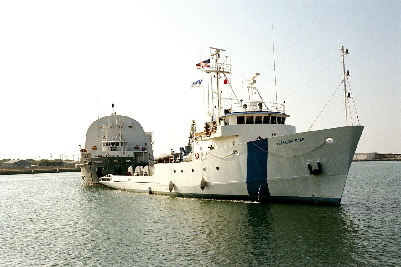 KENNEDY SPACE CENTER, FLA. -- Freedom Star, one of NASA's two solid rocket booster recovery ships, tows a barge containing the third Space Shuttle super lightweight external tank (SLWT) into Port Canaveral. This SLWT will be used to launch the orbiter Discovery on mission STS-95 in October. This first-time towing arrangement, part of a cost savings plan by NASA to prudently manage existing resources, began June 12 from the Michoud Assembly Facility in New Orleans where the Shuttle's external tanks are manufactured. The barge will now be transported up the Banana River to the LC-39 turn basin using a conventional tugboat. Previously, NASA relied on an outside contractor to provide external tank towing services at a cost of about $120,000 per trip. The new plan allows NASA's Space Flight Operations contractor, United Space Alliance (USA), to provide the same service directly to NASA using the recovery ships during their downtime between Shuttle launches. Studies show a potential savings of about $50,000 per trip. The cost of the necessary ship modifications should be paid back by the fourteenth tank delivery. The other recovery ship, Liberty Star, has also undergone deck strengthening enhancements and will soon have the necessary towing winch installed