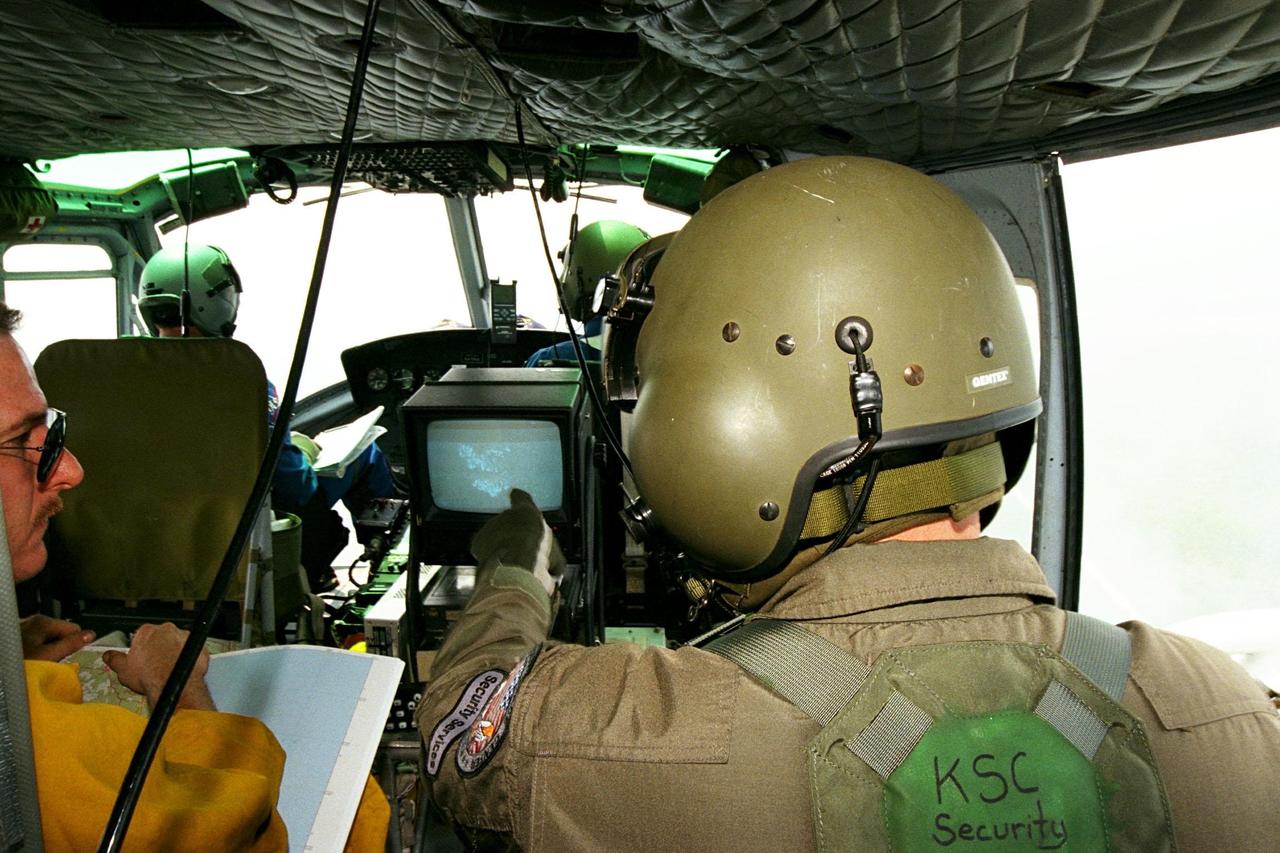 KENNEDY SPACE CENTER, FLA. --  Sgt. Mark Hines, of Kennedy Space Center (KSC) Security, points out a view of a fire on the Forward Looking Infrared Radar (FLIR) video screen to Greg Dunn, of Florida's Division of Forestry, as KSC pilots fly NASA's Huey UH-1 helicopter over fires burning in Volusia County, Florida. The FLIR includes a beach-ball sized infrared camera that is mounted on the helicopter's right siderail and a real-time TV monitor and recorder installed inside. The helicopter has also been outfitted with a portable global positioning satellite (GPS) system to support the Division of Forestry as they fight the brush fires which have been plaguing the state as a result of extremely dry conditions and lightning storms. While the FLIR collects temperature data and images, the GPS system provides the exact coordinates of the fires being observed and transmits the data to the firefighters on the ground. KSC's security team routinely uses the FLIR equipment prior to Shuttle launch and landing activities to ensure that the area surrounding the launch pad and runway are clear of unauthorized personnel. KSC's Base Operations Contractor, EG&G Florida, operates the NASA-owned helicopter.