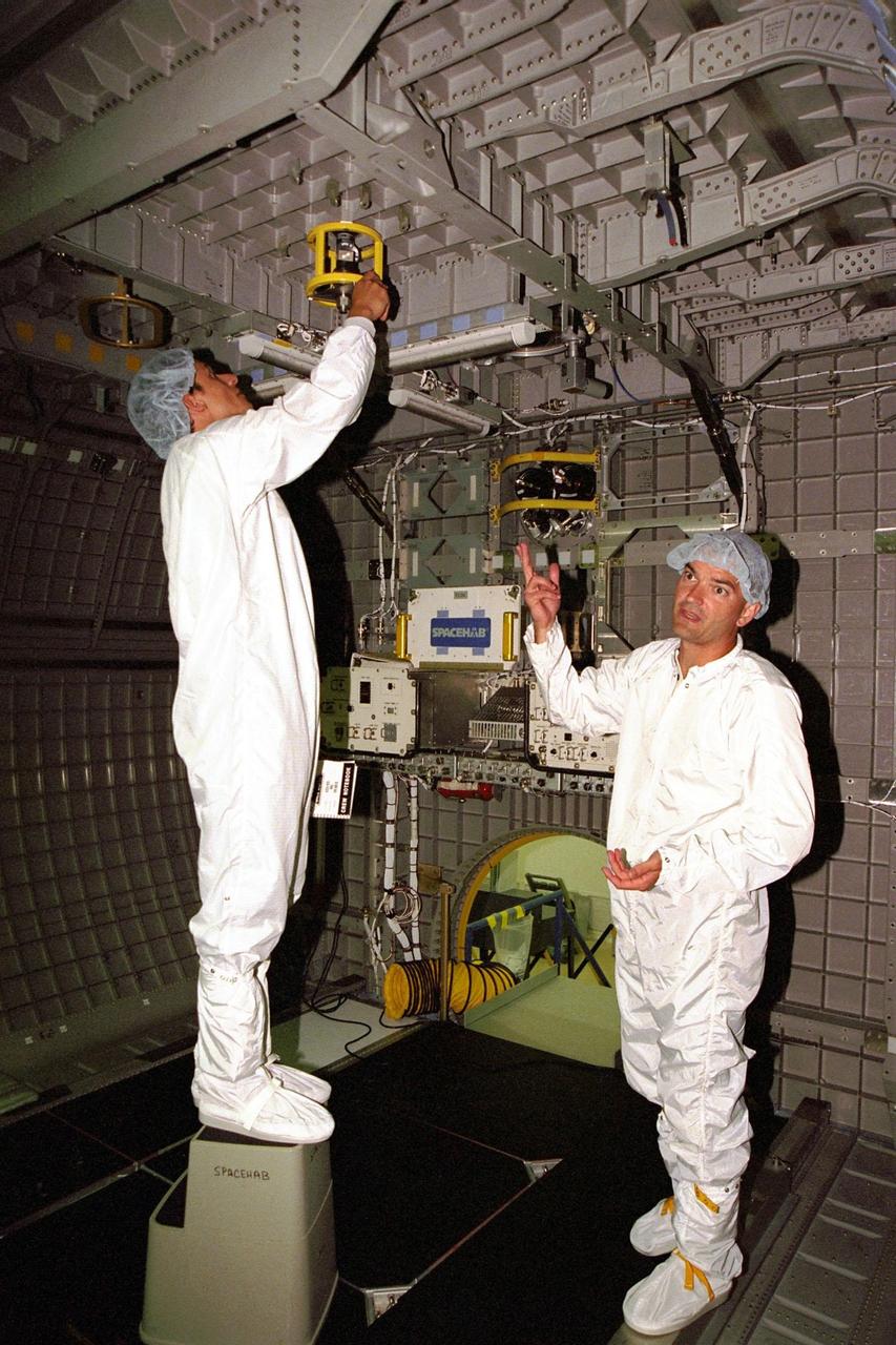 STS-95 Mission Specialist Stephen K.Robinson (left) looks at equipment in the SPACEHAB module as Chris Jaskolka, of Boeing SPACEHAB, explains the equipment during a familiarization tour for the STS-95 crew at SPACEHAB Payload Processing Facility at Cape Canaveral, Fla. The STS-95 is scheduled to launch Oct. 29, 1998. The mission includes research payloads such as the Spartan solar-observing deployable spacecraft, the Hubble Space Telescope Orbital Systems Test Platform, the International Extreme Ultraviolet Hitchhiker, as well as the SPACEHAB single module with experiments on space flight and the aging process